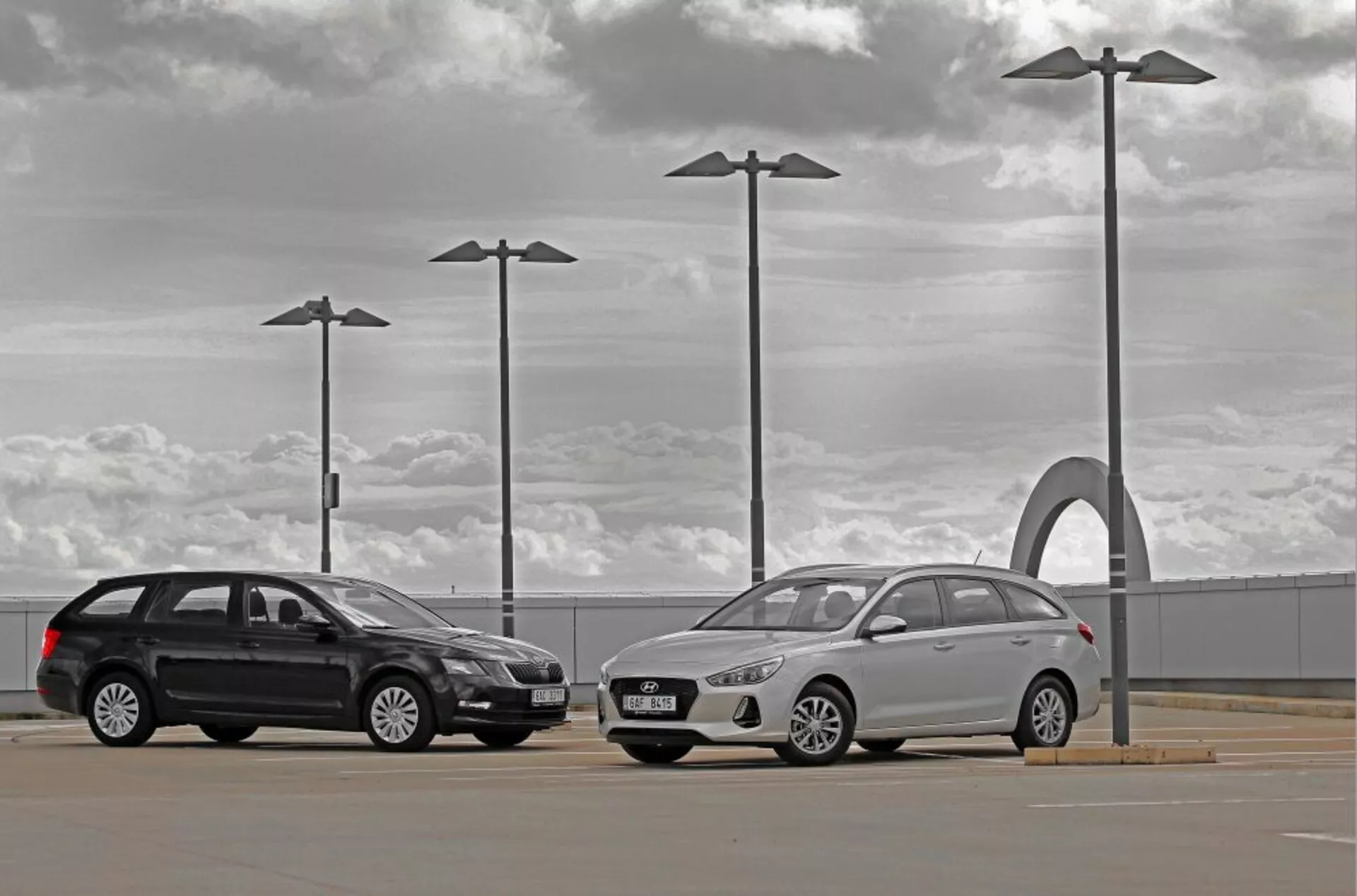 Hyundai i30 2017 kombi i sedan na zewnętrznym parkingu pod zachmurzonym niebem z elementami miejskiego designu