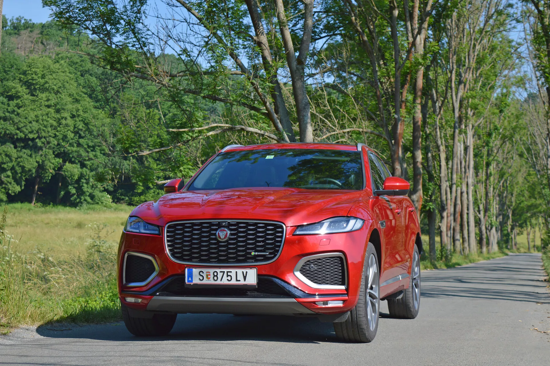 Luksusowy SUV Jaguar F-Pace 2021 w eleganckim srebrnym kolorze, uchwycony podczas dynamicznej jazdy po mieście, podkreślający charakterystyczny przedni grill, reflektory LED i sportowe felgi aluminiowe.