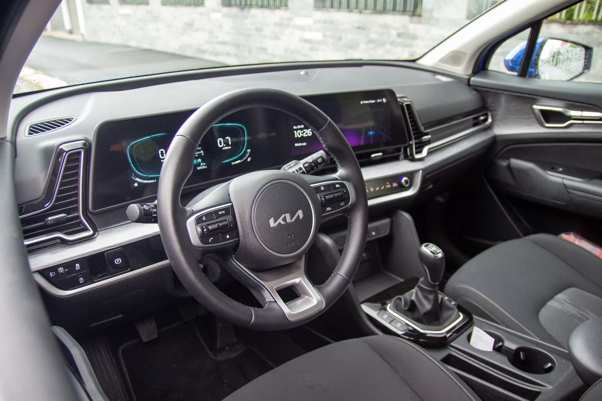 Wnętrze Kia Sportage 2022 z kierownicą z przyciskami sterującymi, cyfrowym zestawem wskaźników i ekranem systemu infotainment