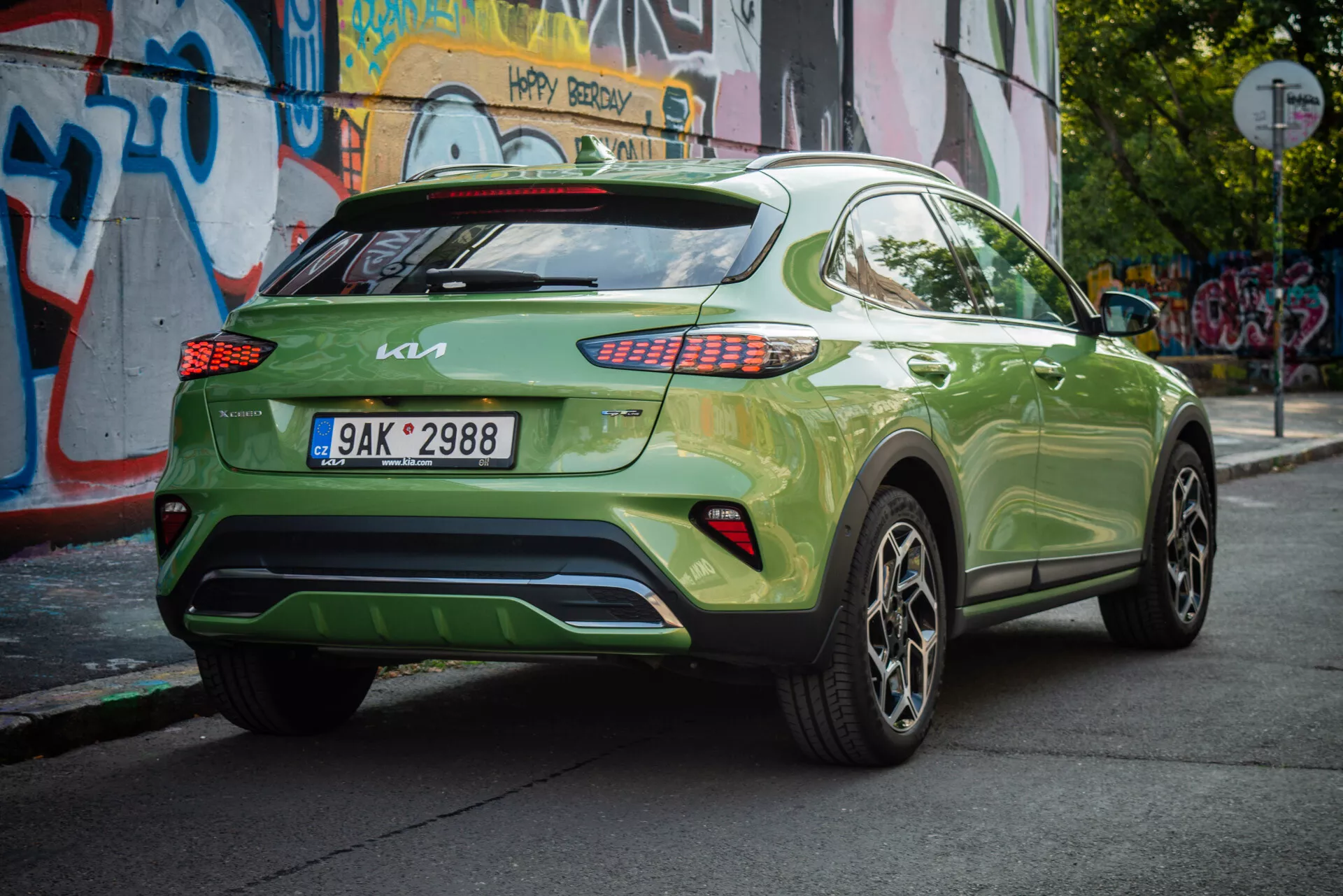 Kia XCeed 2022 w jaskrawym zielonym kolorze, prezentująca swój tylny trójkwartalny kąt z europejską tablicą rejestracyjną, tylnymi lampami LED, aluminiowymi felgami i miejskim tłem.