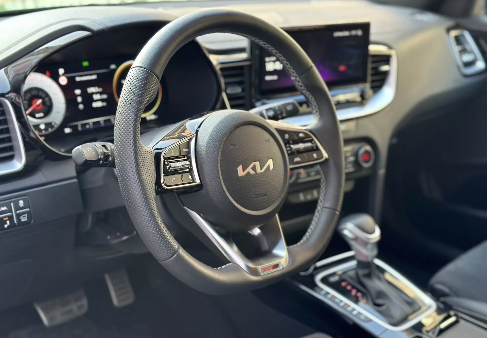 Wnętrze Kia Xceed 2022 skupiające się na stronie kierowcy z kierownicą, cyfrowym zestawem wskaźników i centralnym systemem multimedialnym dotykowym, wskazującym na nowoczesną technologię i wygodę