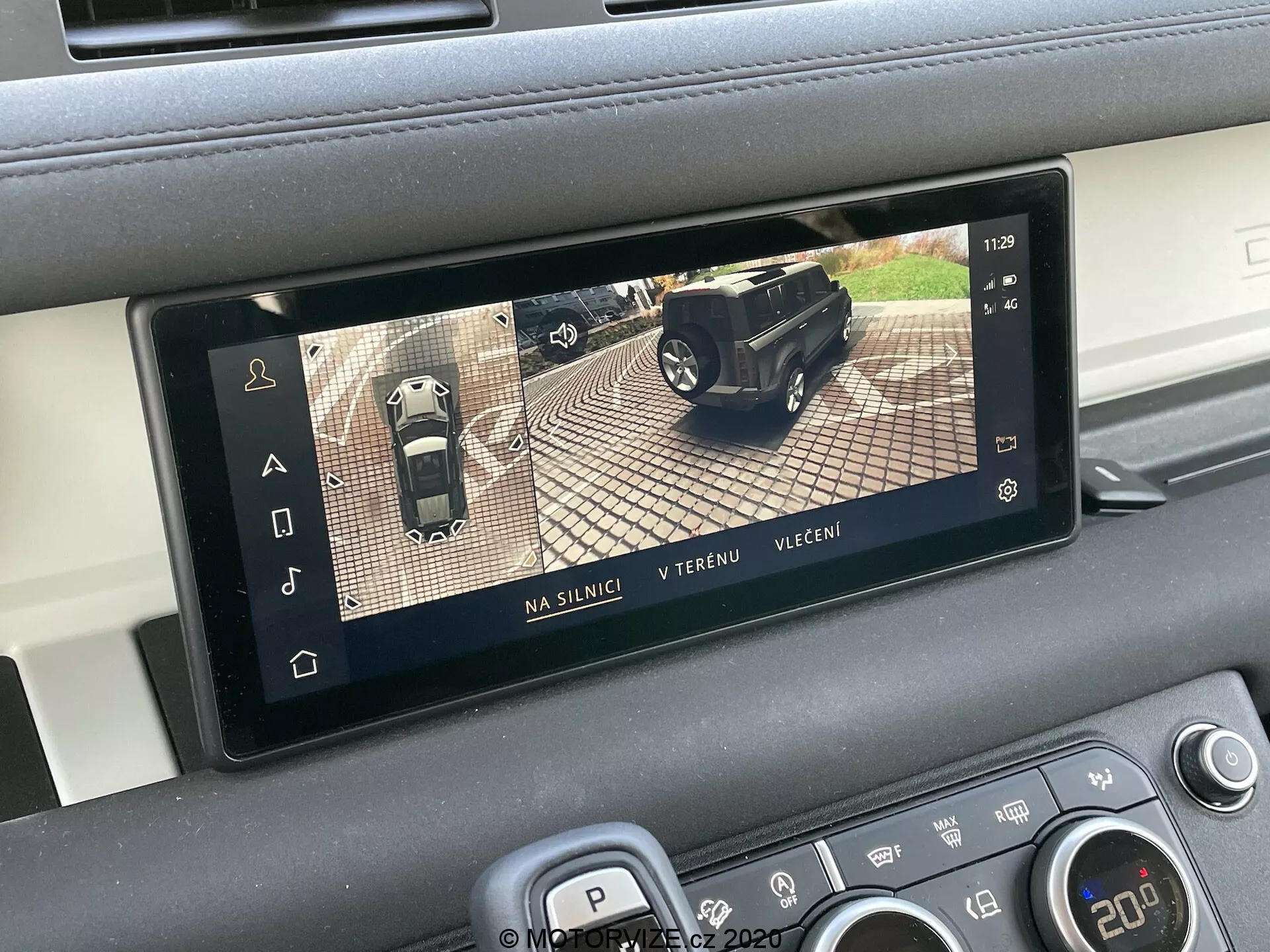 Wnętrzowy wyświetlacz Land Rover Defender 2020 prezentujący system kamer 360 stopni, będący częścią zaawansowanych systemów wspomagania kierowcy (ADAS). Prostokątny ekran jest zintegrowany z konsolą środkową pojazdu i pokazuje trzy tryby widoku: drogowy, terenowy i wieczorny. Wyświetlacz pomaga podczas parkowania i manewrowania, łącząc obrazy z wielu kamer wokół samochodu.
