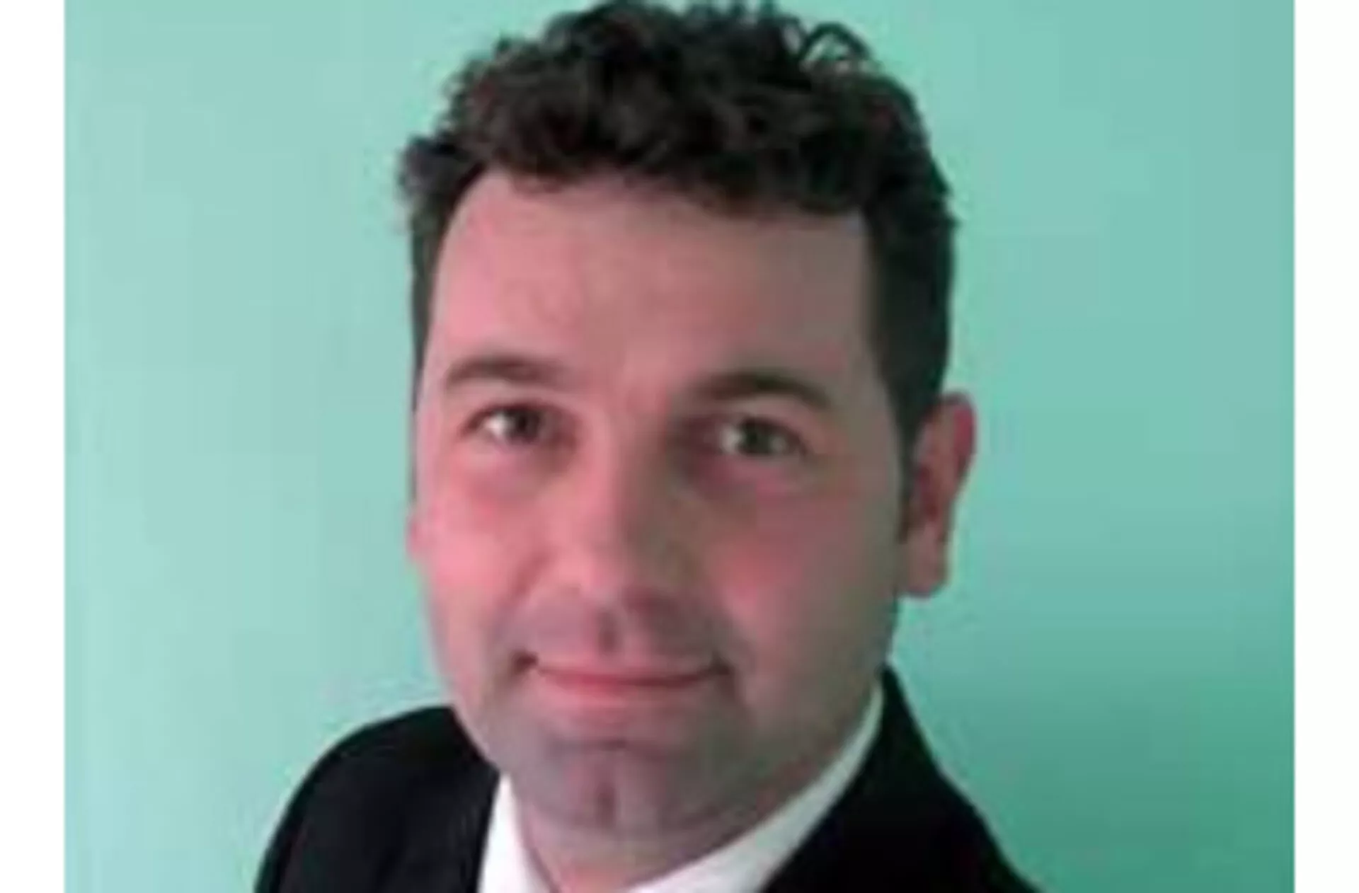 Zdjęcie profesjonalne mężczyzny o krótkich ciemnych włosach, ubranego w garnitur na jasnym tle