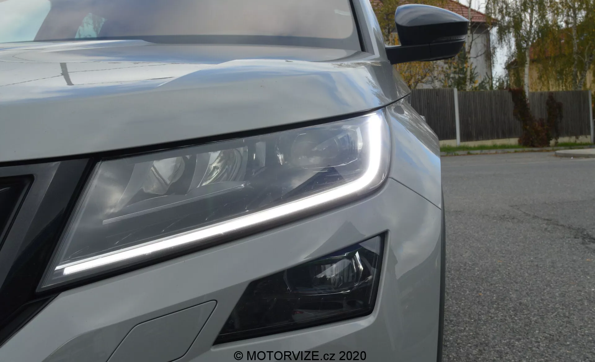 Zbliżenie lewego przedniego boku Skoda Kodiaq 2017, prezentujące zaawansowany zestaw reflektorów LED z dziennymi światłami i soczewkami projektorowymi. Kąt podkreśla technologię i nowoczesne cechy wzornictwa, w tym dodatkowe światła przeciwmgielne, część kratki, maskę z metalicznym wykończeniem oraz lusterko boczne z wbudowanymi kierunkowskazami.