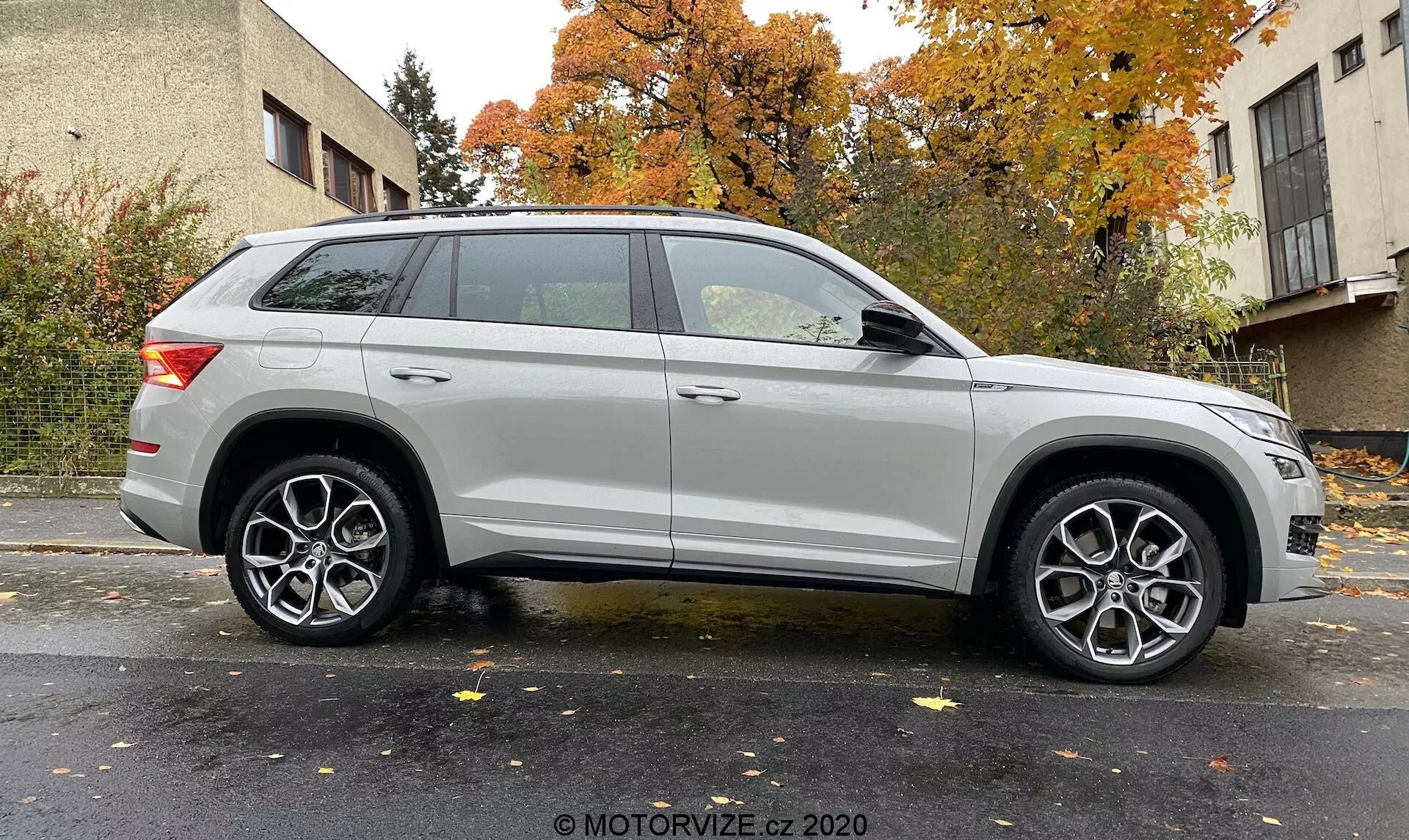 Profil boczny srebrnego SUV-a Skoda Kodiaq 2017 uchwycony pod lekkim kątem, podkreślający przednie koło i błotnik. Pokazuje długość pojazdu i elementy stylistyczne, takie jak nowoczesne reflektory, wieloramienne felgi aluminiowe, wyraźną linię charakteru, relingi dachowe i eleganckie tylne światła. Neutralne tło z równomiernym oświetleniem. Zdjęcie: MOTORVIZE.cz 2020.