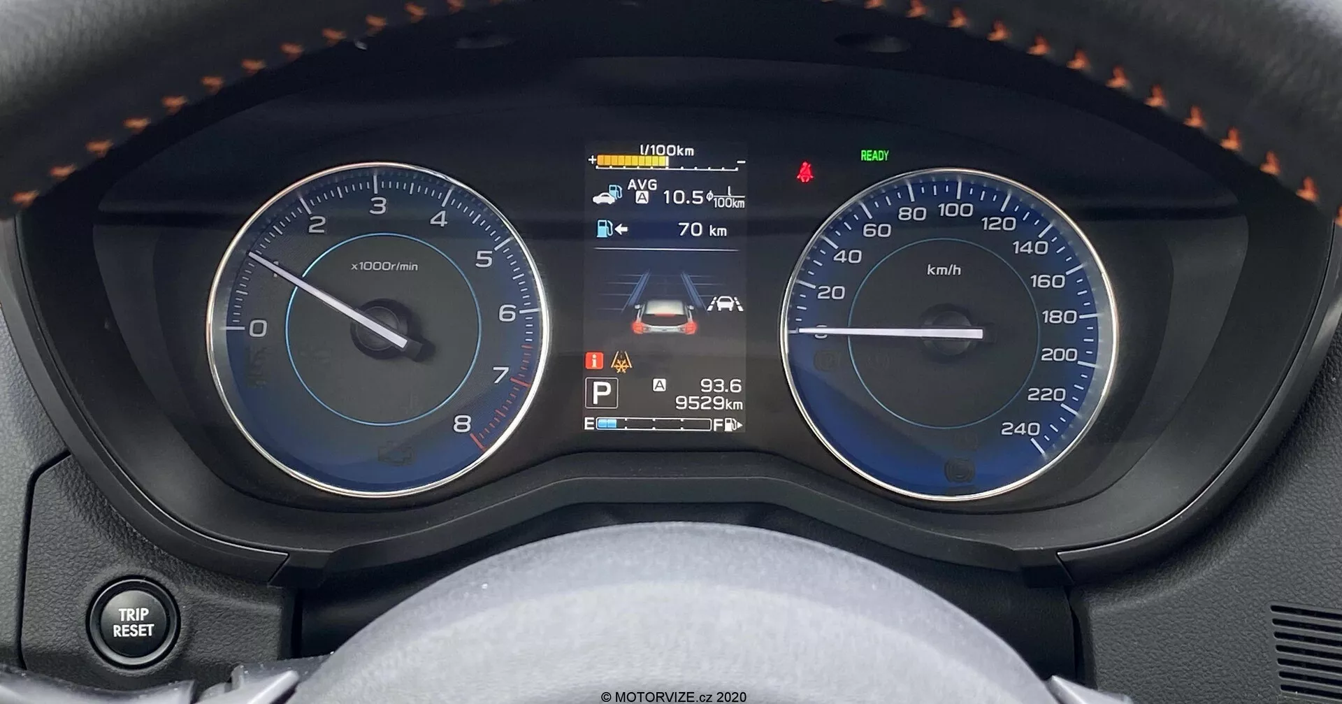 Zbliżenie na panel instrumentów Subaru XV 1.6i Trend Lineartronic, pokazujący analogowy obrotomierz, cyfrowy wyświetlacz wielofunkcyjny i analogowy prędkościomierz. Centralny wyświetlacz cyfrowy pokazuje wskaźnik paliwa, stan pojazdu, temperaturę zewnętrzną 10,5°C, ostrzeżenie o konserwacji, bieg w pozycji P, odometer o przebiegu 95,249 km i godzinę 9:36. Obraz przedstawia deskę rozdzielczą z perspektywy kierowcy, z dodatkowymi elementami, takimi jak dźwignia sterowania światłami i kierunkowskazami po lewej stronie oraz częściowy widok na kierownicę z podpórkami na kciuki i przeszyciami.