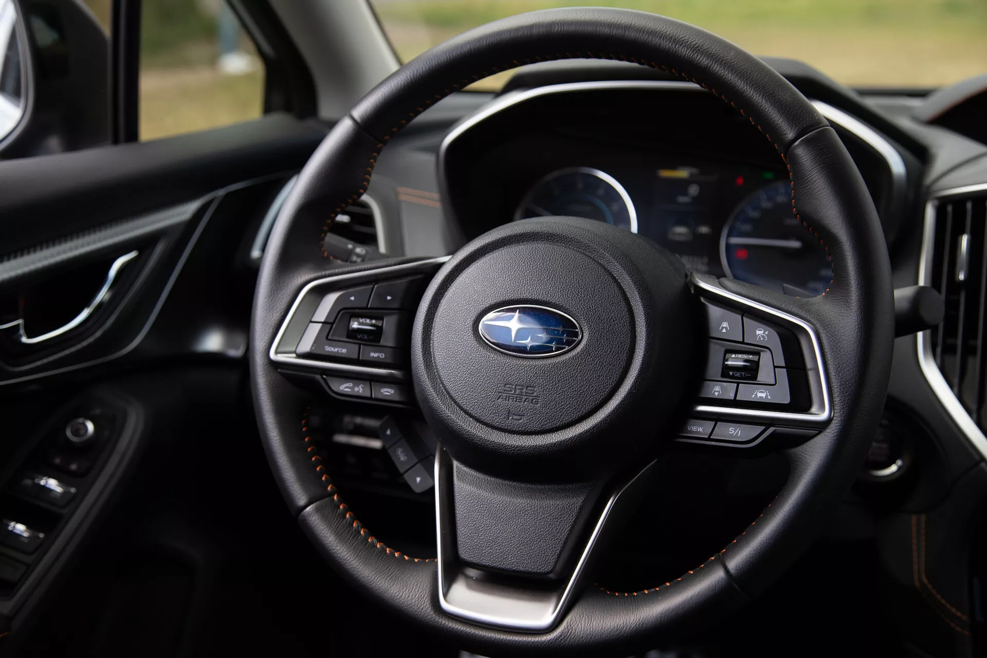 Zbliżenie na kierownicę Subaru XV 2021 z multifunkcyjnymi przyciskami, luksusowym wykończeniem ze skóry i nowoczesnym deskiem rozdzielczym z cyfrowymi wyświetlaczami