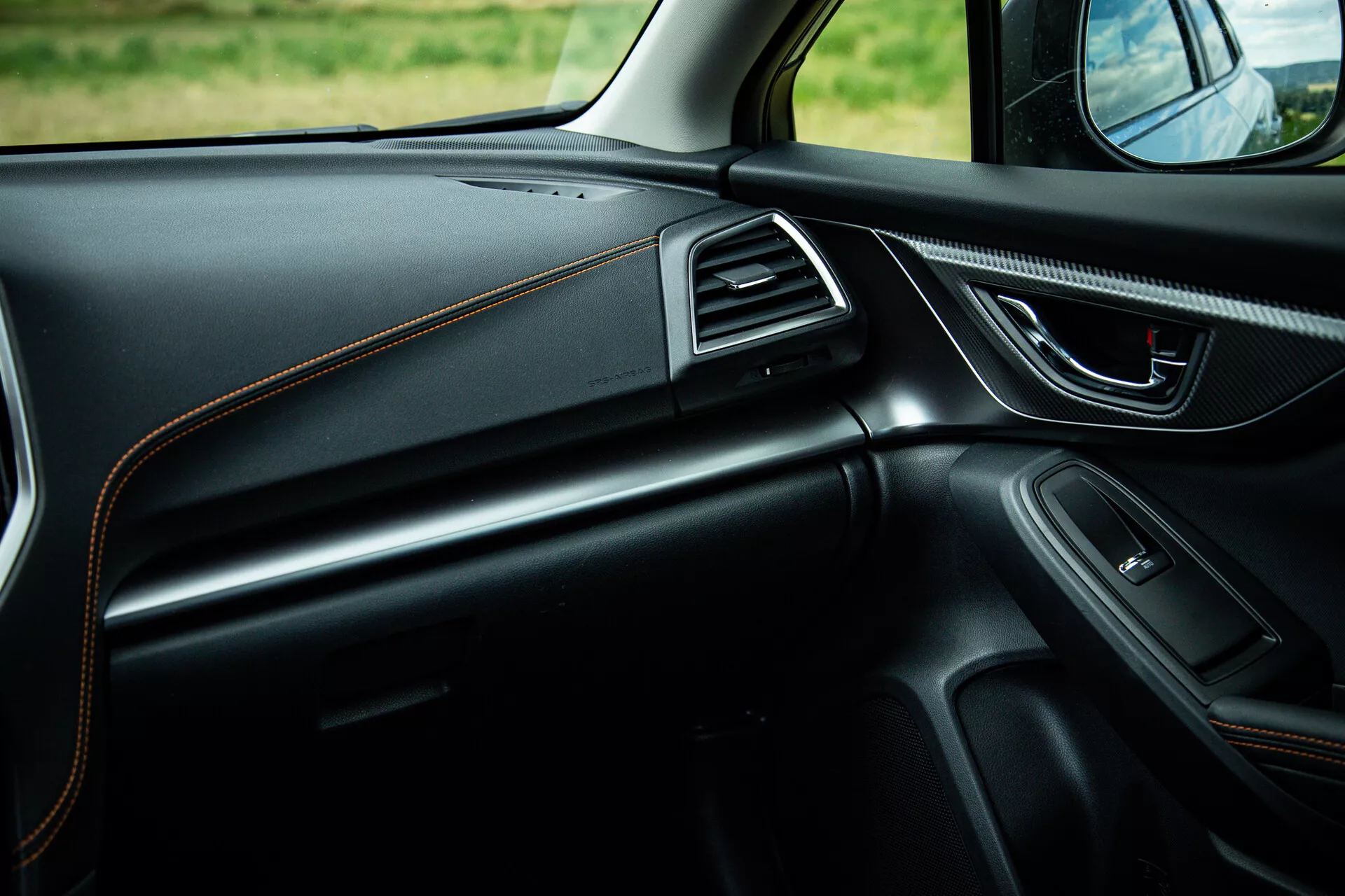 Wnętrze Subaru XV 2021 ze skupieniem na stronę pasażera prezentujące elegancki design deski rozdzielczej z kontrastowymi szwami, ergonomiczną klamkę drzwi z kontrolami elektrycznymi, wbudowany głośnik, chromowane akcenty nawiewów i oświetlenie ambientowe