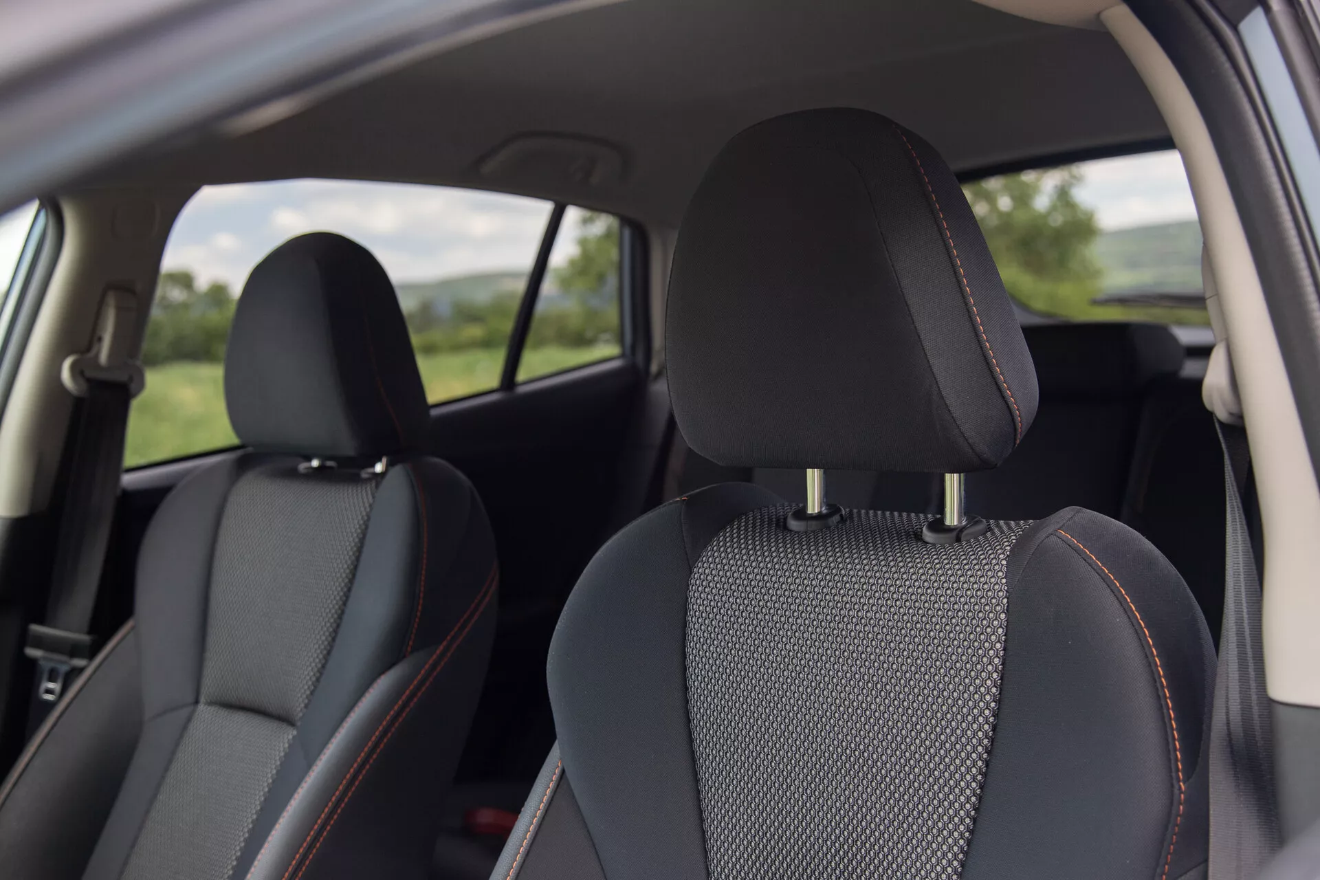 Widok wnętrza Subaru XV 2021 featuring czarne skórzane siedzenia z wstawkami z wzorzystego materiału i charakterystycznymi pomarańczowymi szwami, skupiający się na komforcie i designie z perspektywy tylnej strony