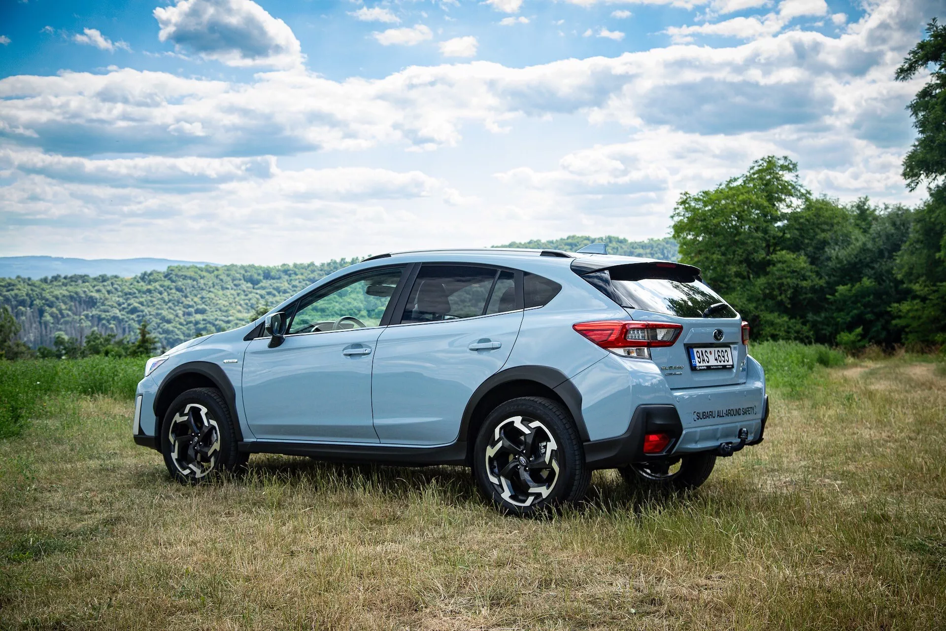 Jasno zabarwiony SUV fotografowany z perspektywy trzy czwarte od tyłu ukazujący boczny i tylny design z wieloramienne felgi aluminiowe, przyciemniane szyby oraz potencjalne funkcje technologiczne, zaparkowany w naturalnym otoczeniu