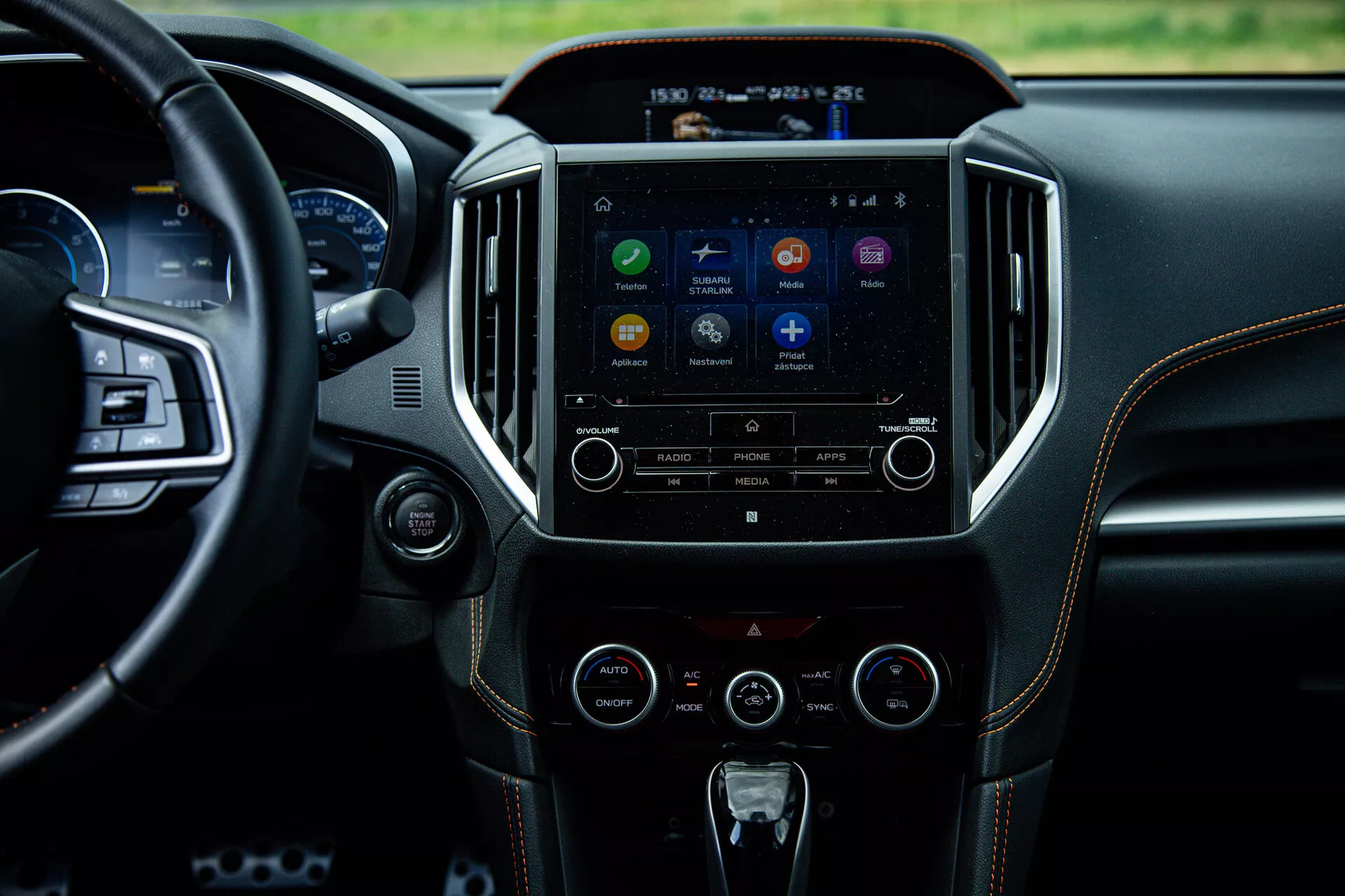 Wnętrze Subaru XV 2021 z akcentem na konsolę środkową i system infotainment z perspektywy tylnej kanapy, przedstawiające ekran dotykowy z ikonami aplikacji, przyciski sterowania audio i klimatyzacją, odzwierciedlające zaawansowaną technologię i luksusowy design