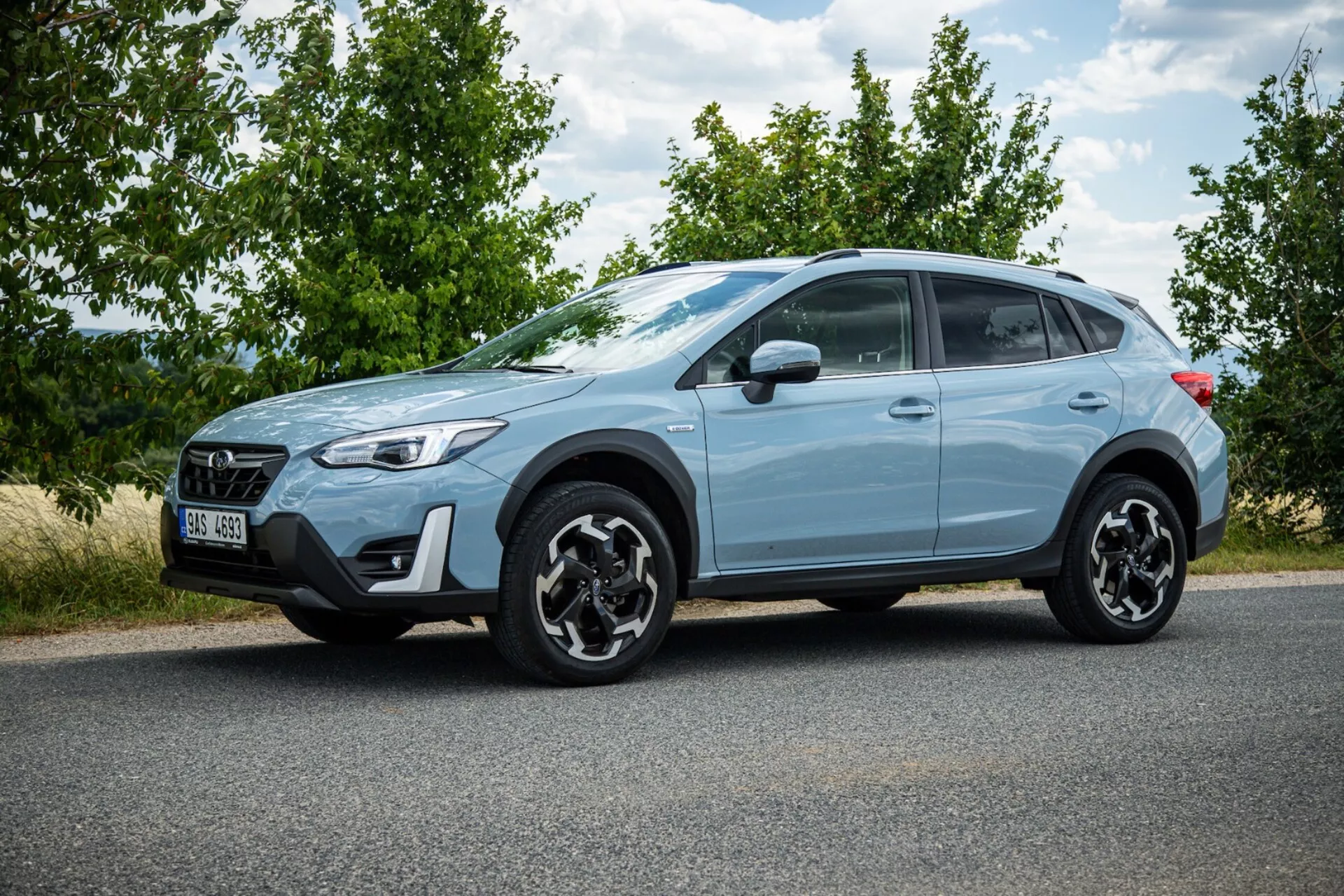 Crossover Subaru XV 2021 w jasnoniebieskim kolorze zaparkowany na asfalcie pokazujący profil boczny, charakterystyczne czarne felgi aluminiowe, tylne światła LED, wysokie prześwit dla użytku miejskiego i lekkiego terenowego oraz nowoczesne funkcje bezpieczeństwa