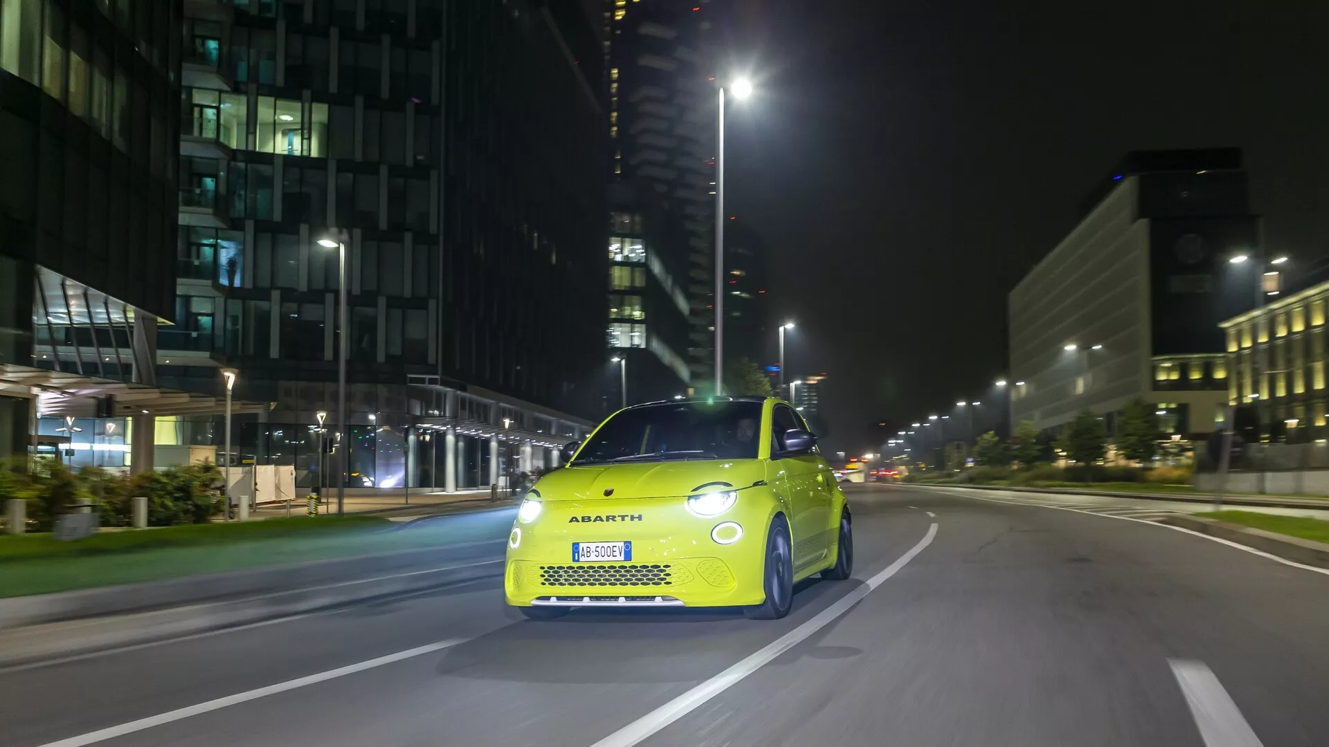Fotografia Abartha 500, 595 i 695 (2. generacja) z 2023 roku, wykonana z prawego przedniego kąta, ukazująca charakterystyczny przedni grill, reflektory LED i sportowe elementy stylistyczne. Samochód jest nieruchomy na miejskiej ulicy, obrazując zarówno techniczne cechy, jak i stylową, kompaktową sylwetkę, która uosabia markę Abarth.