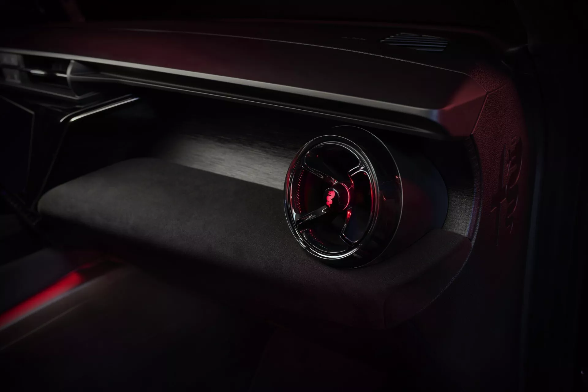 Zbliżenie na wnętrze Alfa-Romeo Junior 2024 z naciskiem na deskę rozdzielczą po stronie pasażera z podświetlaną nawiewem i materiałami premium