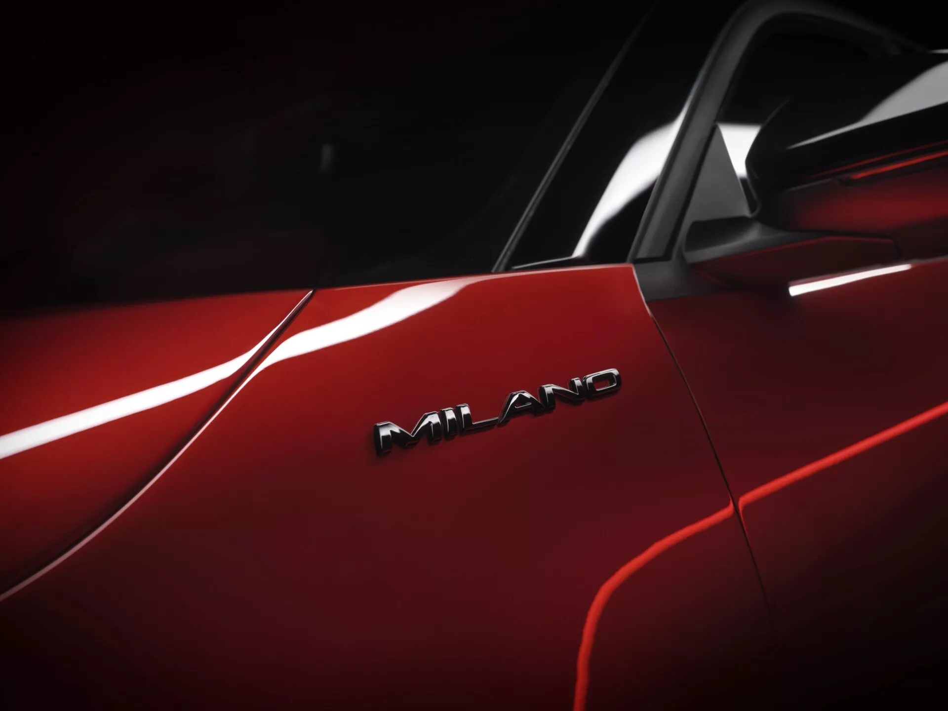 Zbliżenie na czerwony Alfa-Romeo Junior 2024 pokazujący jego błyszczące wykończenie i odznakę AMG, co wskazuje na jego wysoką jakość wykonania i wydajność