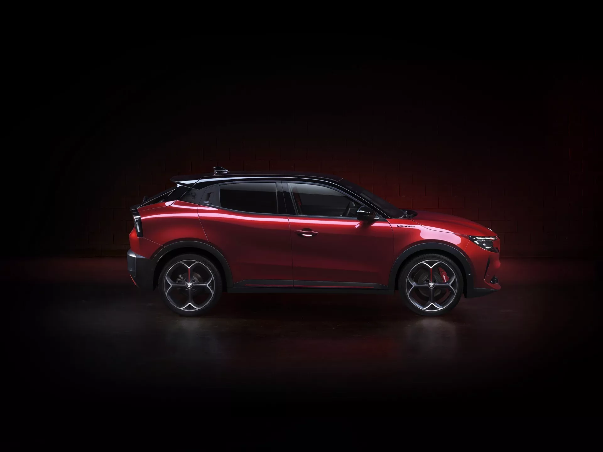 Alfa Romeo Junior (966) z 2024 roku prezentowane w dynamicznym profilu bocznym, podkreślające jego sportowe koła ze stopu, reflektory LED i eleganckie detale konstrukcyjne pod dramatycznym oświetleniem