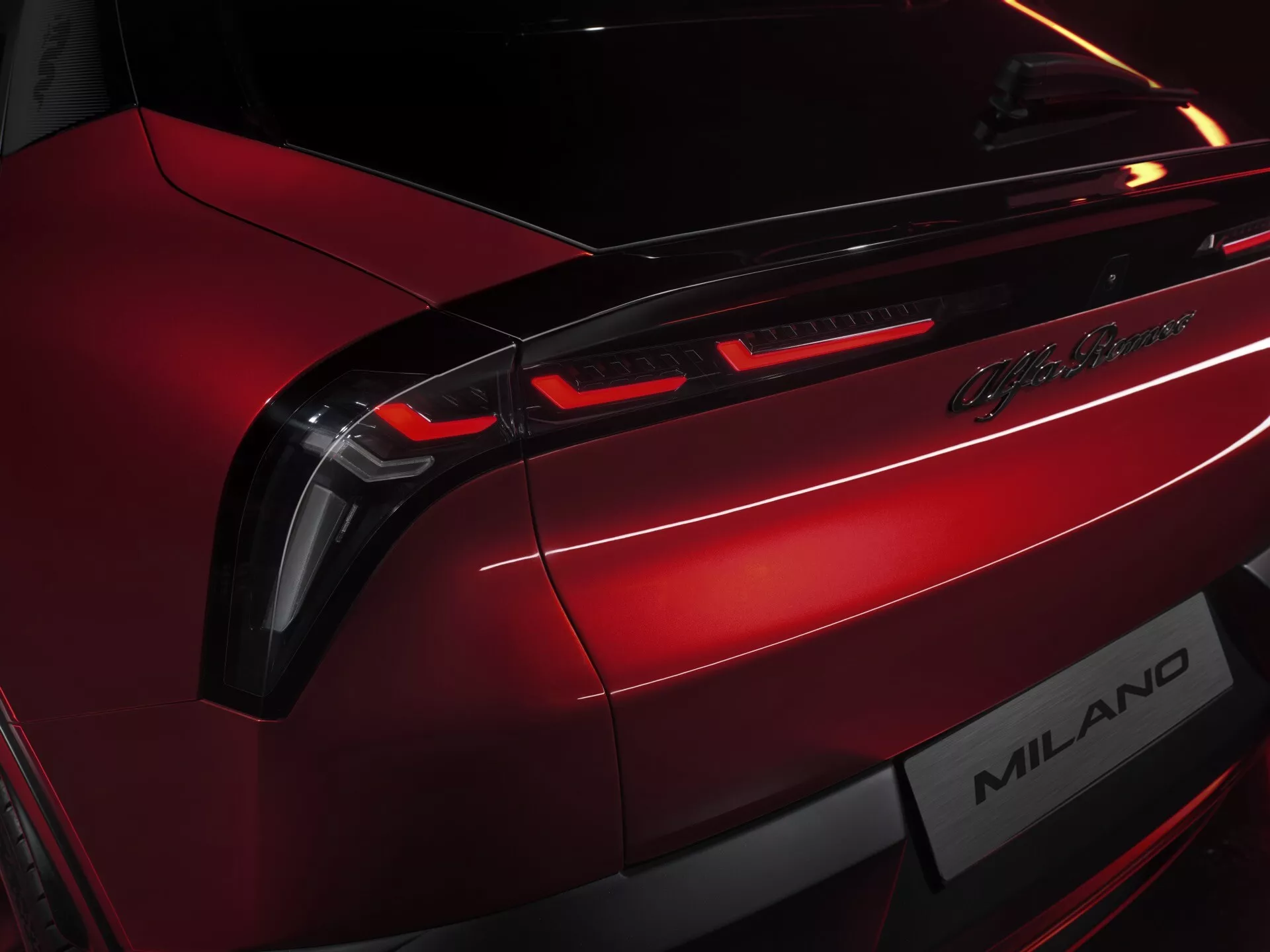 Zbliżenie na tylną część Alfa Romeo Junior 2024, pokazujące tylne światła LED, odznaka Lamborghini Milano, w metalicznym czerwonym