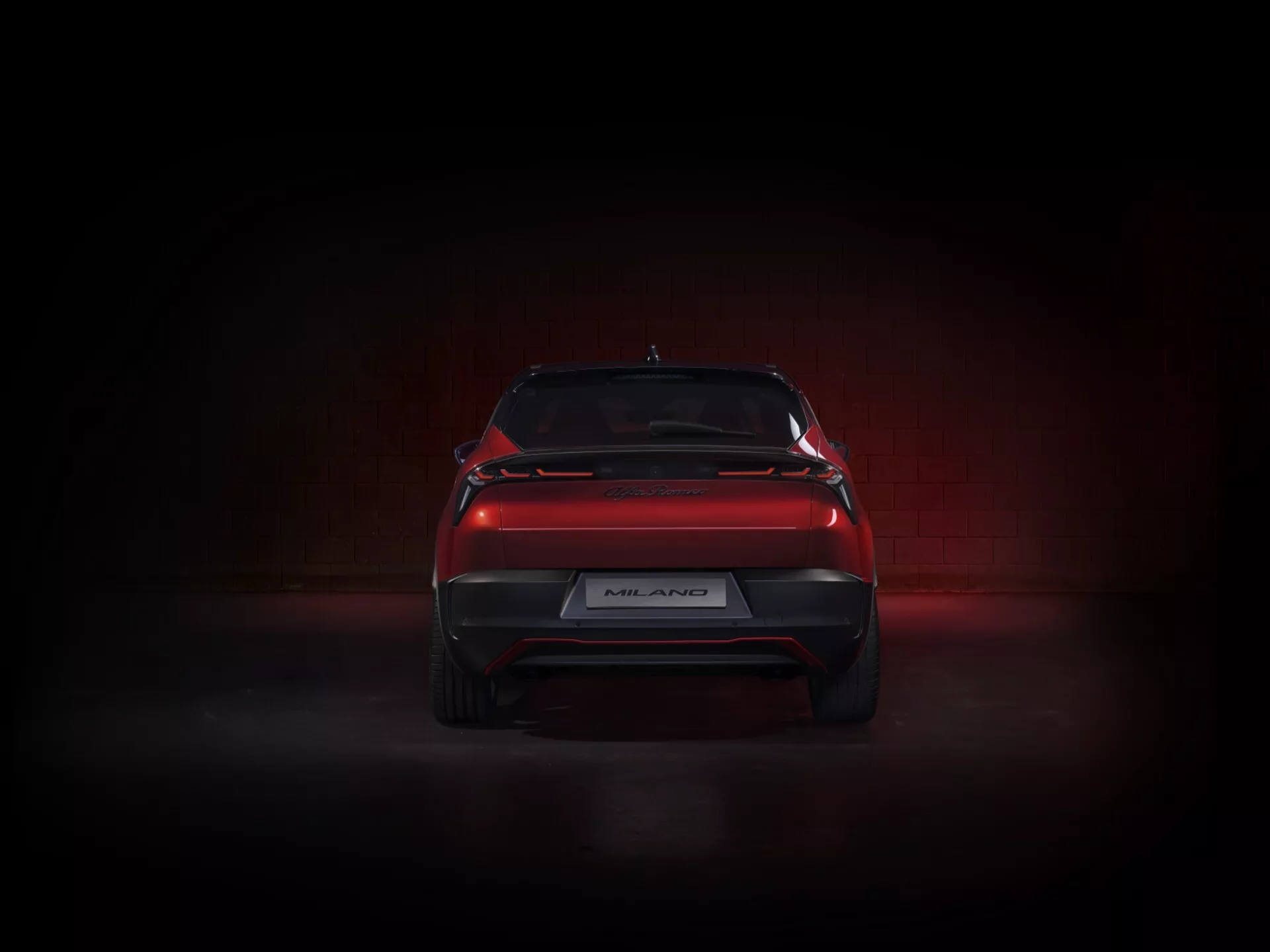 Tył Alfa Romeo Junior 2024 prezentujący elegancki design z tylnymi światłami LED, sportowym dyfuzorem tylnym i spoilerem na pokrywie bagażnika w dramatycznym oświetleniu studyjnym