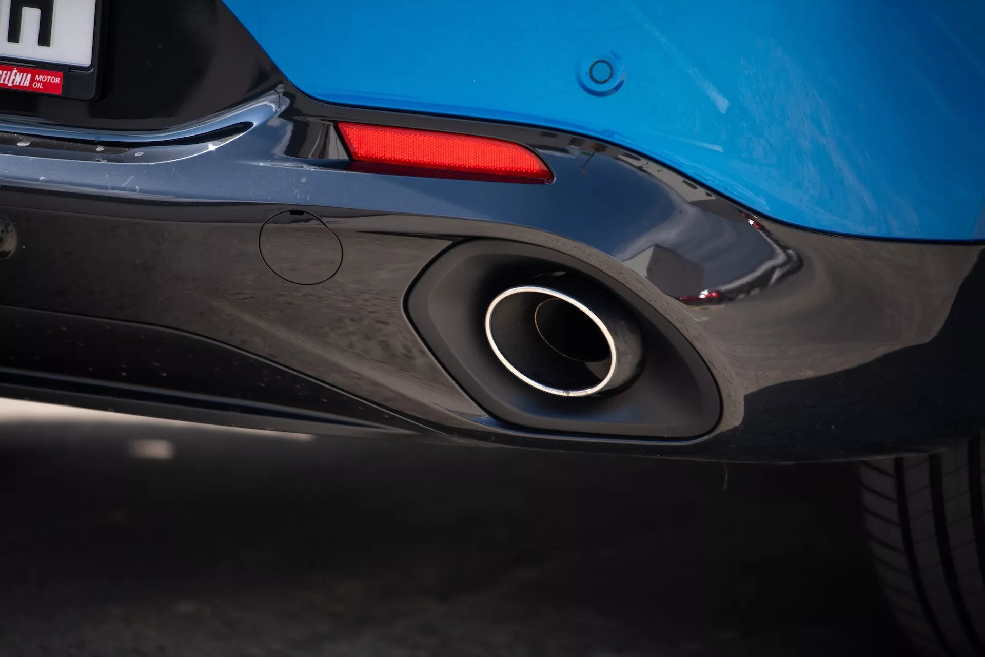 Zbliżenie na tylną część Alfa Romeo Tonale 2022 z podkreśleniem sportowego rury wydechowej, aerodynamicznego designu zderzaka tylnego i niebieskiego koloru karoserii z wglądem na tylne światło