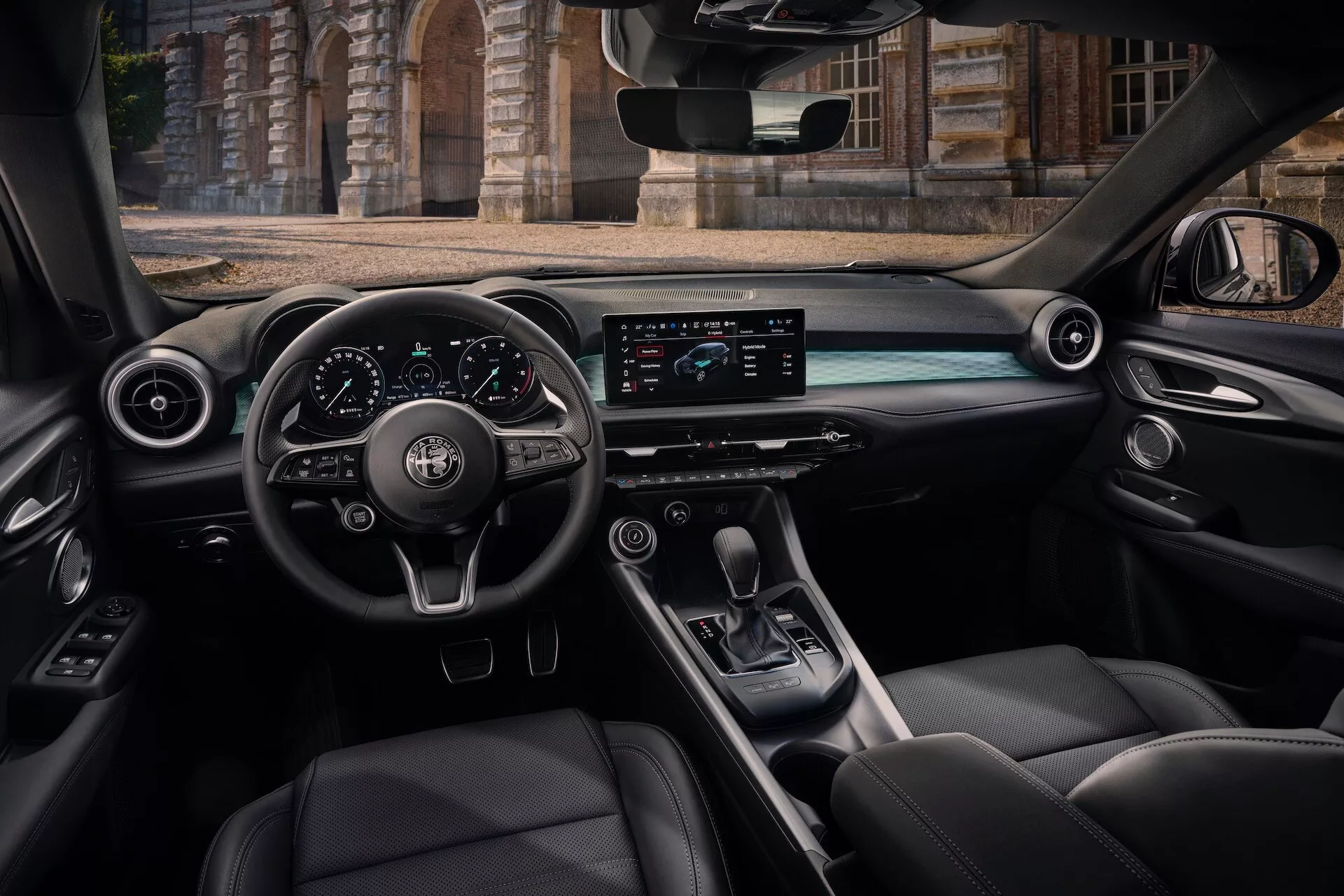 Widok wnętrza Alfa Romeo Tonale 2022 z tylnego siedzenia pasażera przedstawiający kokpit, kierownicę z przyciskami, cyfrowy panel przyrządów, poziomy ekran systemu infotainment, środkową konsolę z dźwignią zmiany biegów i luksusowe skórzane siedzenia