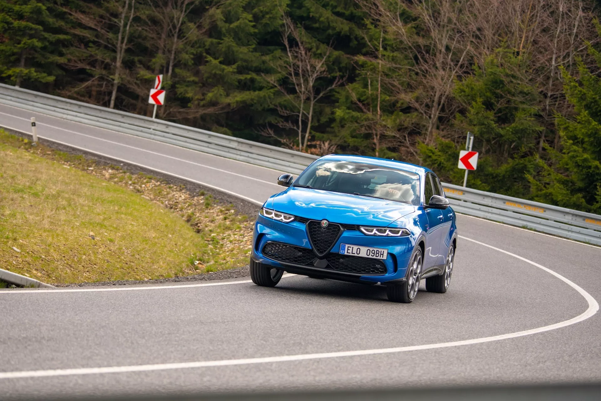 Dynamiczna jazda Alfa Romeo Tonale 2022 na krętej drodze z widokiem na przednią część, reflektory LED, charakterystyczną atrapę i koła do wysokich osiągów
