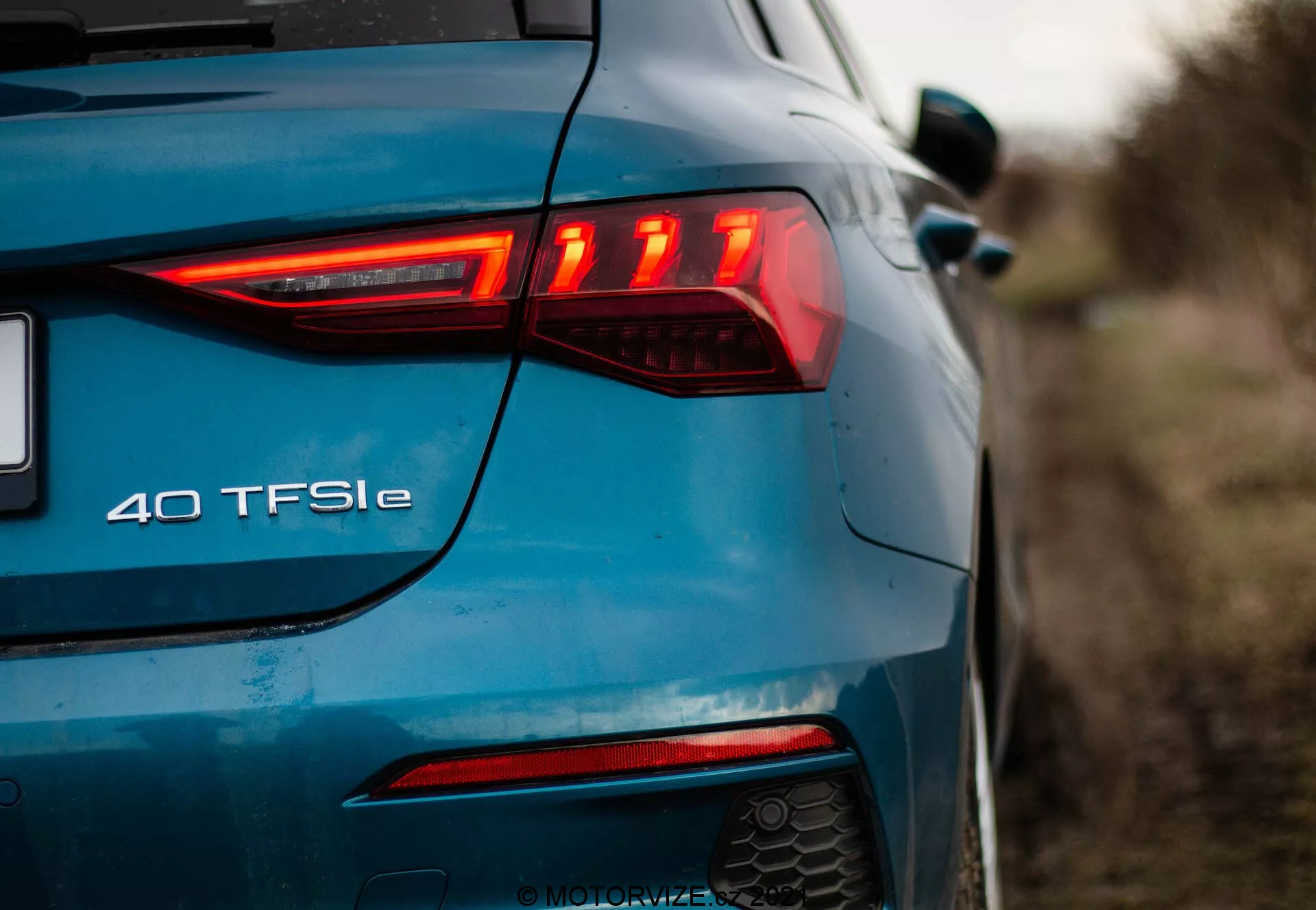 Tylny-lewy kąt niebieskiego Audi A3 2020 Sportback, podkreślający nowoczesny design tylnych świateł LED z poziomymi elementami, tylne światło przeciwmgłowe, podwójny układ wydechowy i emblemat '40 TFSI e' wskazujący na hybrydowy układ napędowy.