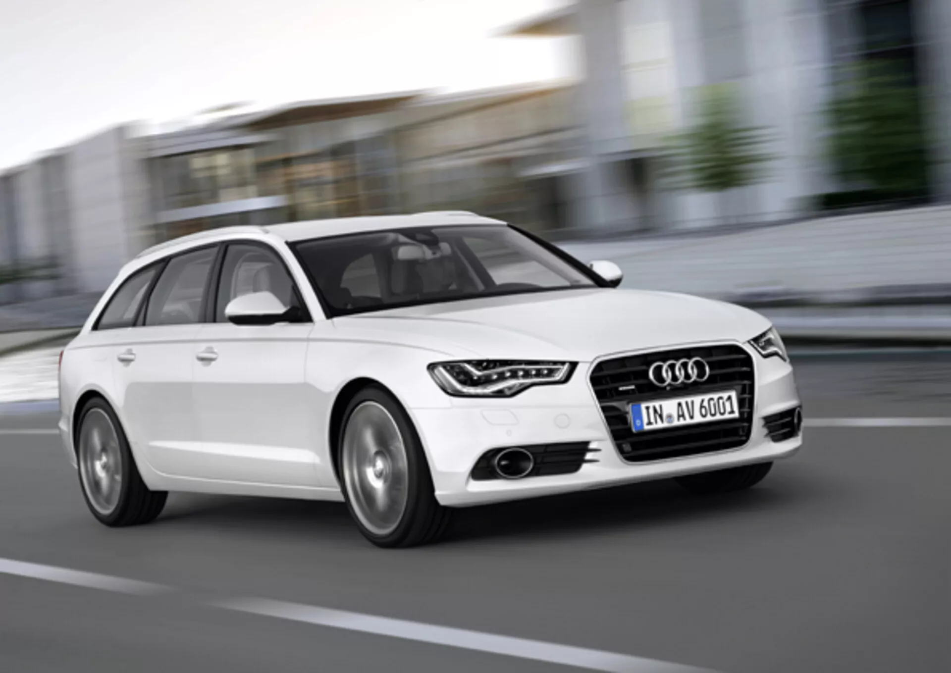 Biały Audi A6 Avant z 2011 roku w ruchu, uchwycony z niskiego kąta przedniego trzy czwarte, podkreślający grill, diodowe światła do jazdy dziennej, felgi aluminiowe i dynamiczny projekt