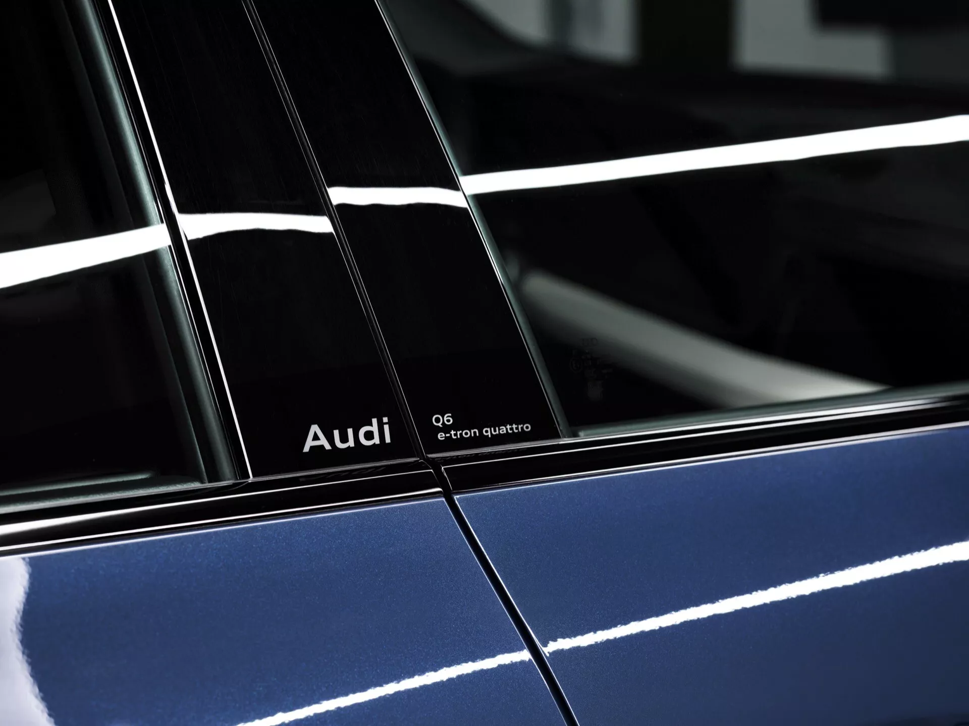 Boczny widok wysokiej rozdzielczości Audi Q6-e-tron quattro 2024 w głębokim niebieskim kolorze z błyszczącym wykończeniem, pokazujący wyraźne oznakowanie i szczegółowe cechy projektu, podkreślający słupek B między drzwiami i refleksyjne oświetlenie.
