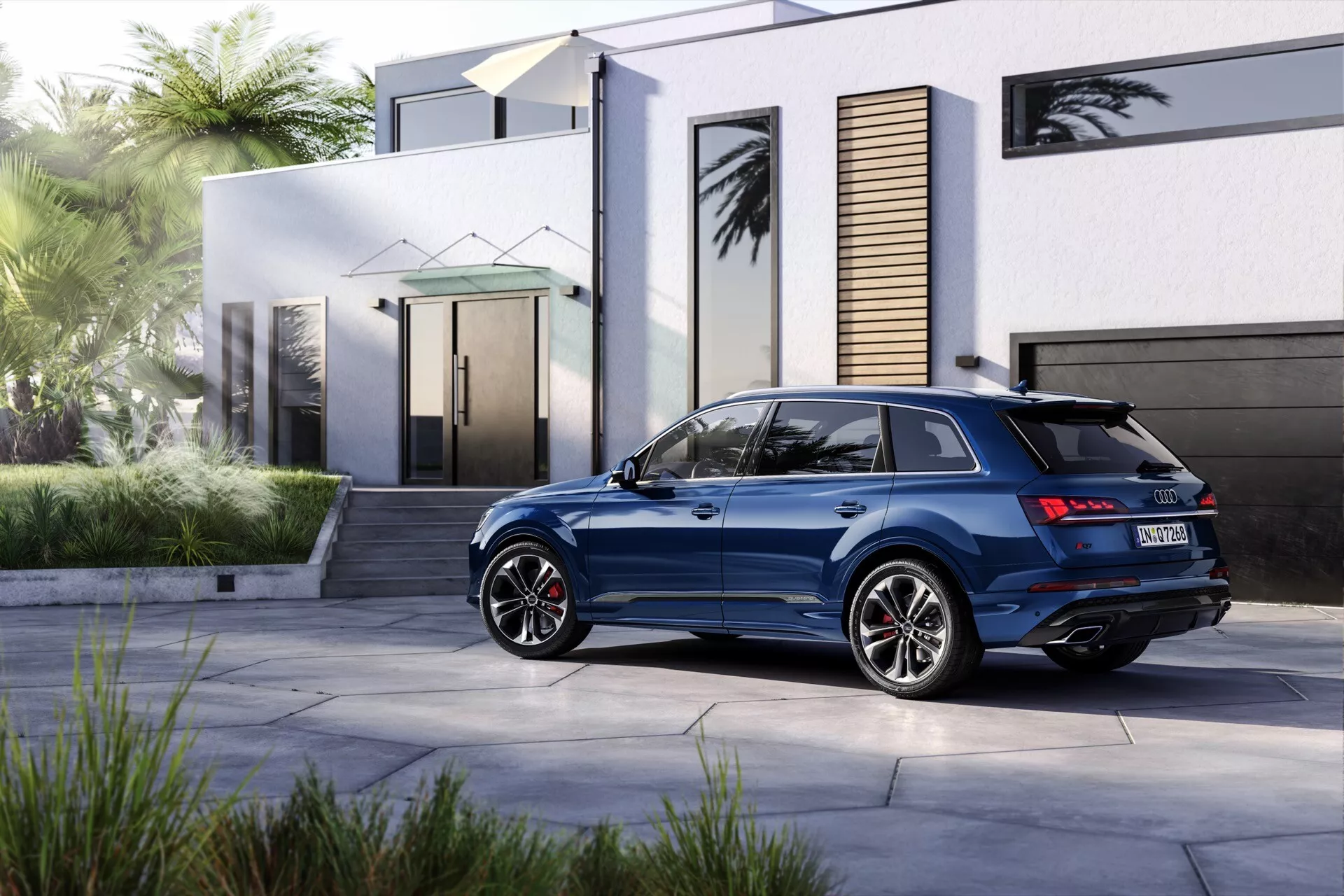 Audi Q7 2024 (4M-Facelift-2) zaparkowane przed nowoczesnym domem, prezentujące jego luksusowe cechy i wydajność, w tym tylne światła LED, spoiler, relingi dachowe, sportowe felgi aluminiowe i podwójne rury wydechowe.