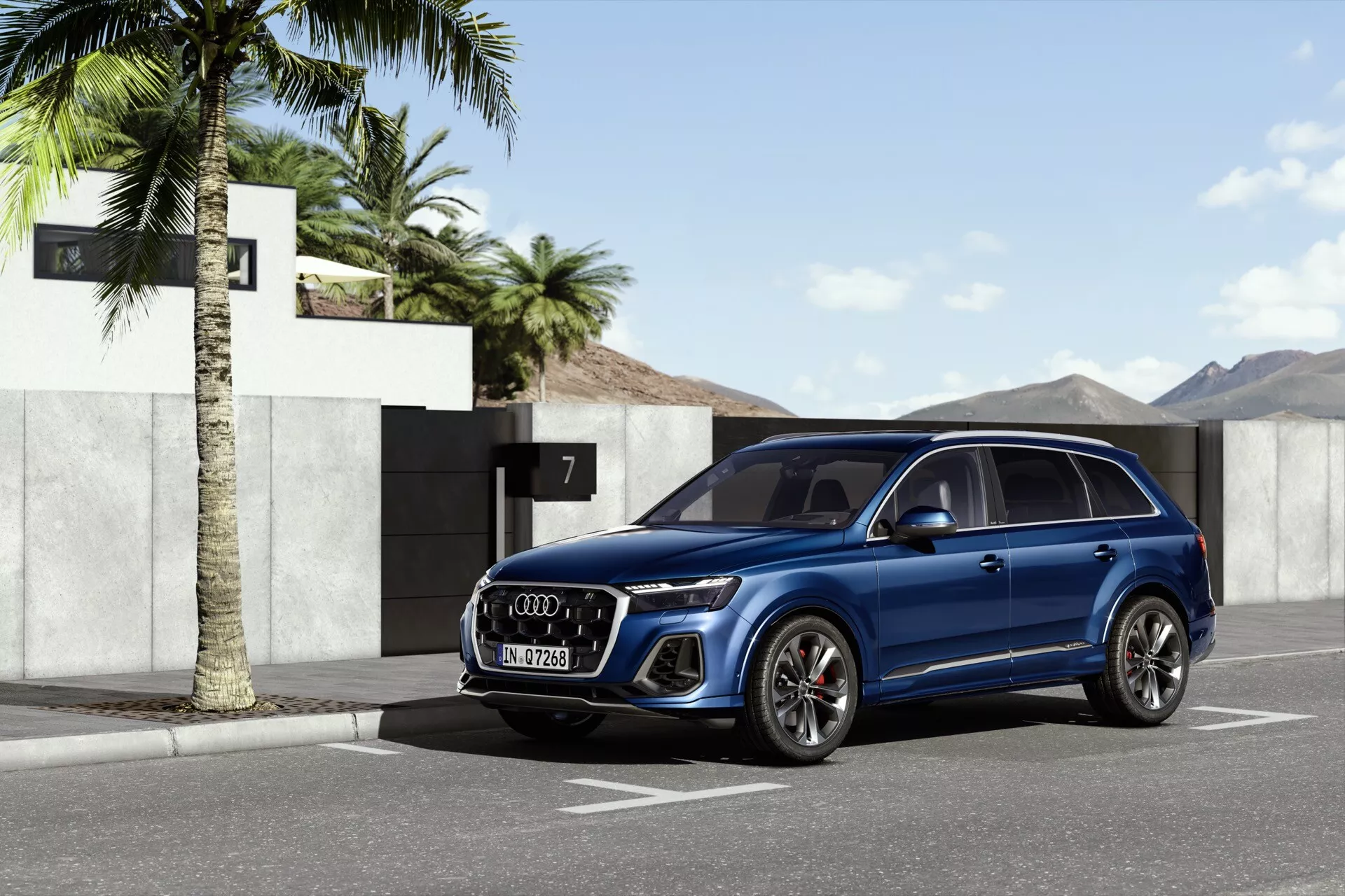 SUV Audi Q7 2024 w metalicznym niebieskim kolorze, zaparkowany na zewnątrz obok palmy z mieszkalnym tłem włącznie z domem numer 7, w słonecznej scenerii