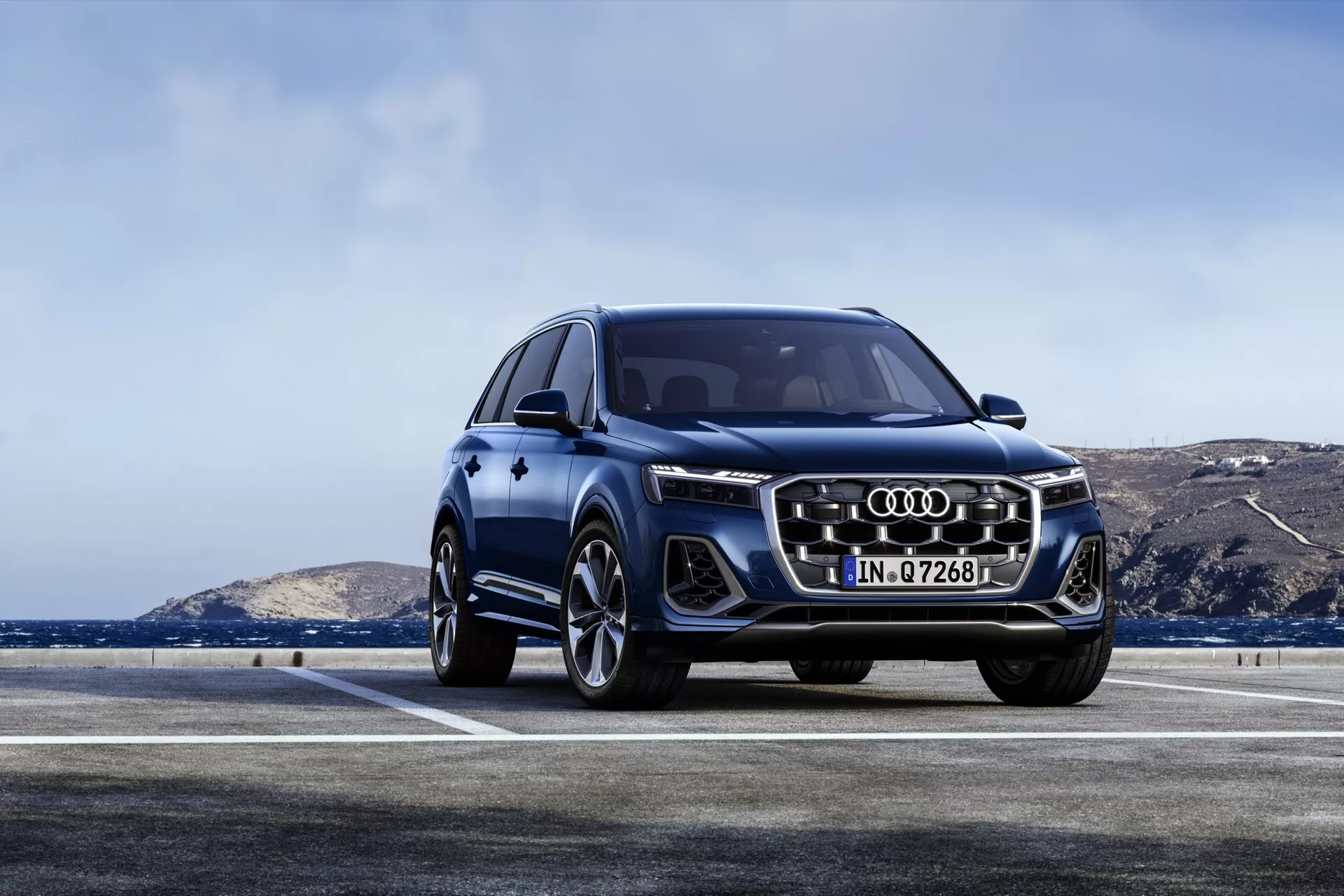 Model Audi Q7 4M facelift 2024 w kolorze niebieskim prezentujący swój dynamiczny design, charakterystyczną przednią atrapę Audi z pionowymi chromowanymi listwami, kątowe reflektory LED i duże felgi aluminiowe na zewnątrz z zamglonym horyzontem w tle