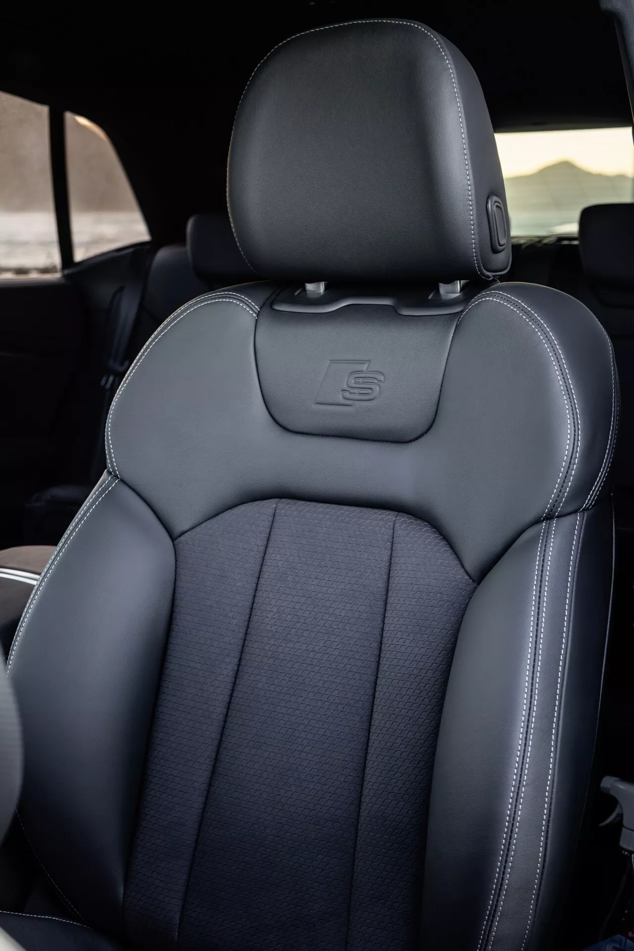 Wnętrze Audi Q8 (4M-Facelift) 2023 skoncentrowane na fotelu kierowcy z detalami szycia, luksusowymi materiałami i sportową ergonomią, częściowo widoczna kierownica wskazująca stronę kierowcy