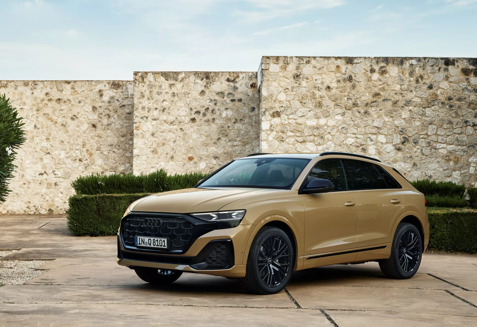 Nowoczesny SUV Audi Q8 2023 (4M-Facelift) w stonowanym złocie, zaparkowany na historycznym dziedzińcu prezentujący przedni grill, eleganckie reflektory i sportowy profil boczny z funkcjami technologicznymi i elementami luksusowego designu w naturalnym świetle