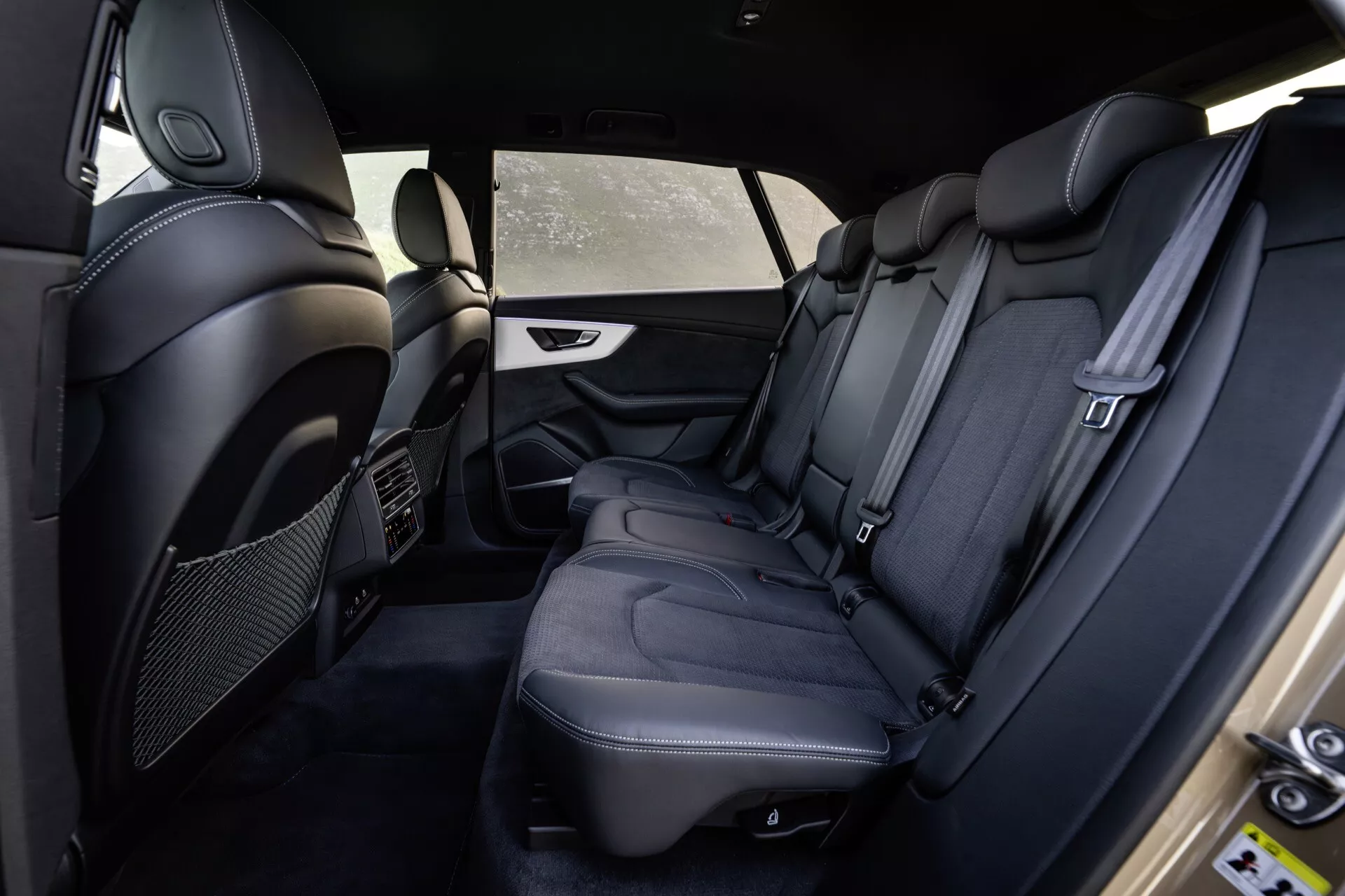 Wnętrze Audi Q8 4M-Facelift 2023 ukazujące tylną część pasażerską od strony kierowcy z premium czarnymi skórzanymi siedzeniami, szczegółowym szyciem, luksusowym wyposażeniem i funkcjami bezpieczeństwa