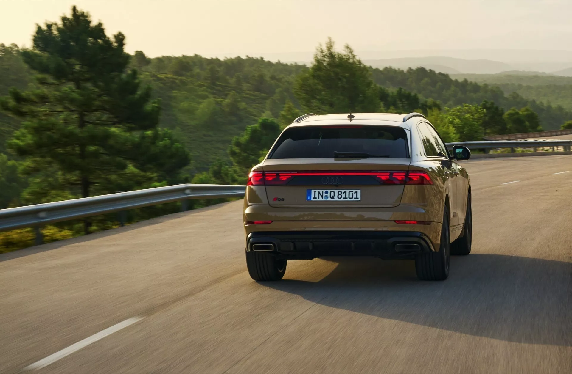 Audi Q8 2023 (4M-Facelift) uchwycone w dynamicznym widoku z tyłu z trzech czwartych podczas jazdy po otwartej drodze, prezentujące pełnowymiarowy design tylnych świateł i podwójne końcówki wydechu
