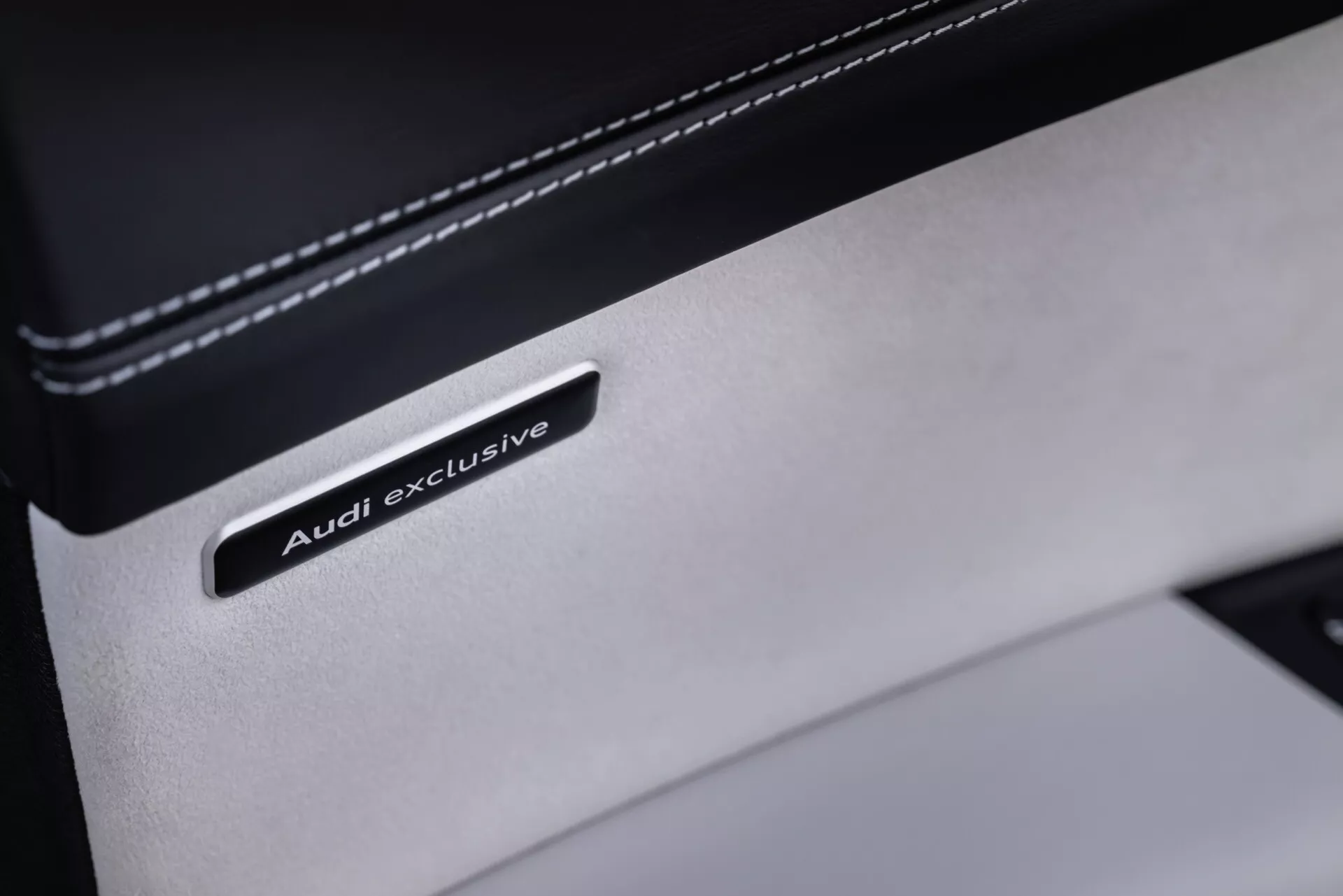 Zbliżenie na odznakę Audi exclusive na szczególe premium skóry we wnętrzu Audi Q8 2023 (4M-Facelift), prezentujące luksusową personalizację i jakość materiału