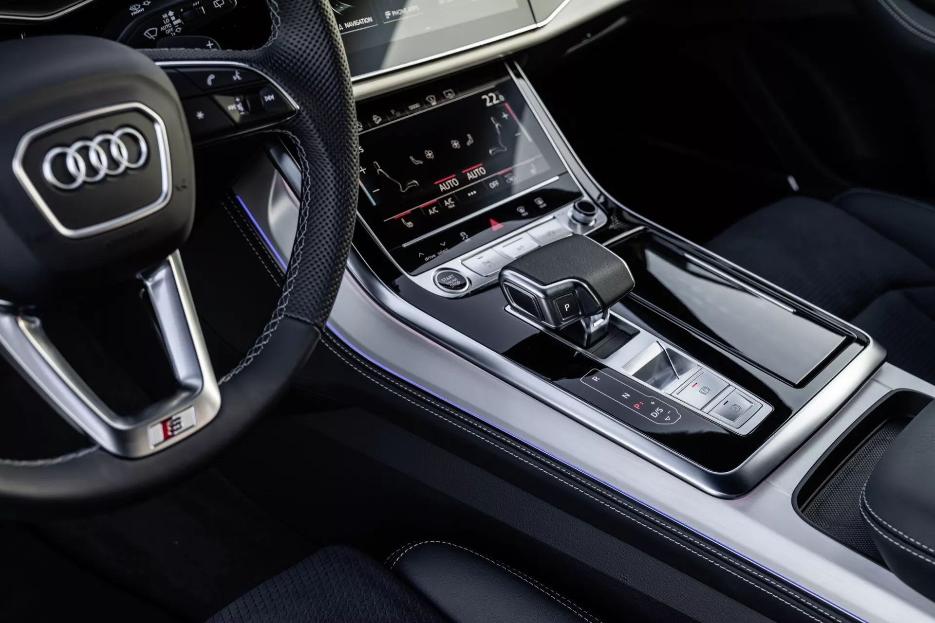 Widok z góry na wnętrze Audi Q8 2023 skupiający się na konsoli środkowej z dźwignią zmiany biegów i panelem sterowania multimediami, podkreślający luksusowe wykończenia i zaawansowane funkcje technologiczne