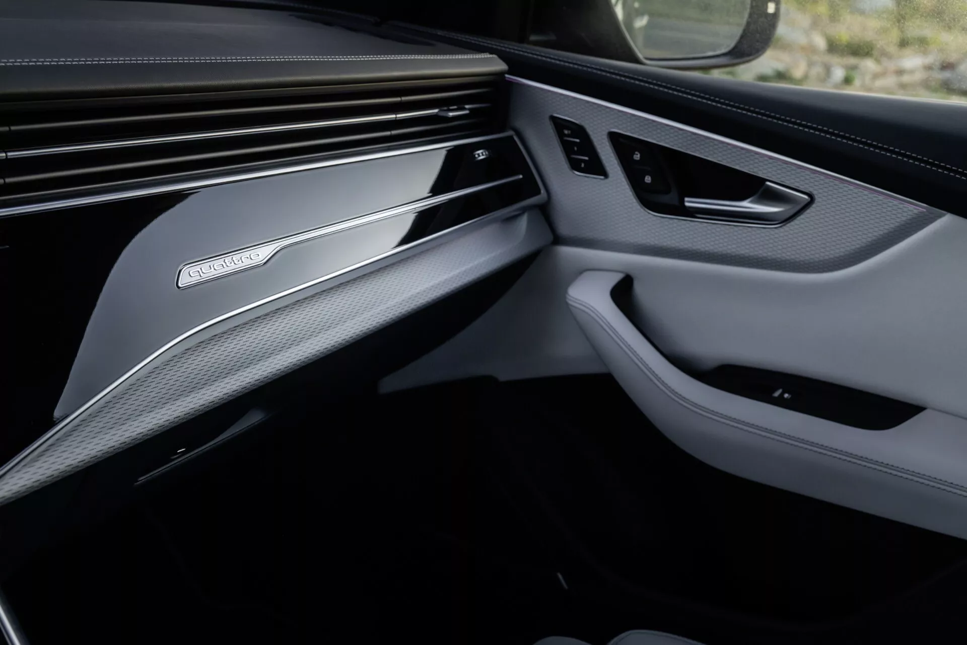 Zdjęcie wnętrza Audi Q8 2023 (4M-Facelift) skupiające się na luksusowym designie strony pasażera przedniego, w tym szczegółowy widok deski rozdzielczej i panelu drzwi z materiałów premium i funkcji technologicznych
