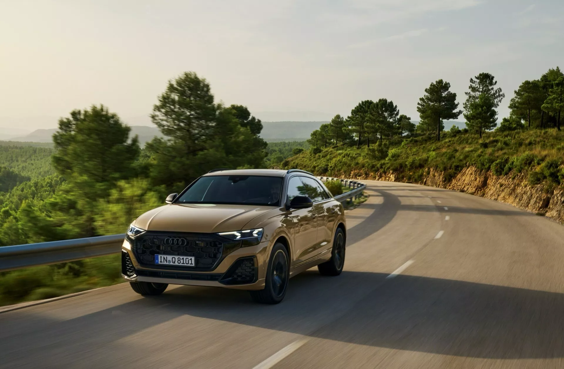 Audi Q8 4M Facelift 2023 poruszające się po wiejskiej drodze, prezentujące reflektory LED, heksagonalną kratę, sportowe kontury maski i zaawansowane technologie asystenta kierowcy