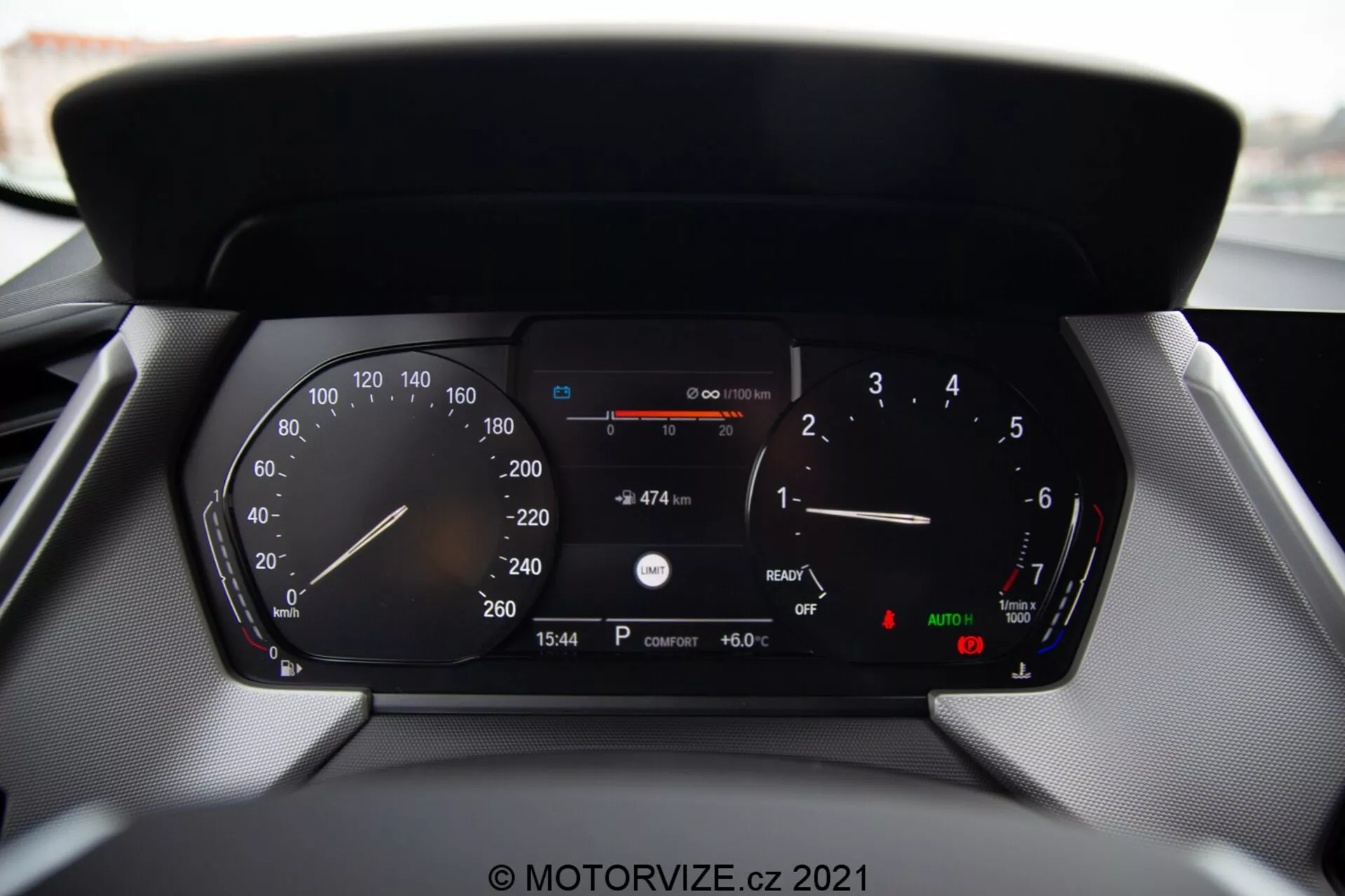 Zbliżenie na cyfrowy zestaw wskaźników współczesnego samochodu BMW Serii 1 2019 (BMW 116i), pokazujący szczegółowe odczyty, w tym prędkościomierz, obrotomierz, wskaźnik poziomu paliwa, wskaźnik temperatury, cyfrowy odczyt prędkości, pozostałą odległość z aktualnym paliwem, wyświetlacz czasu (15:54), temperaturę zewnętrzną (6.0°C) oraz wskaźniki świateł automatycznych i hamulca ręcznego.