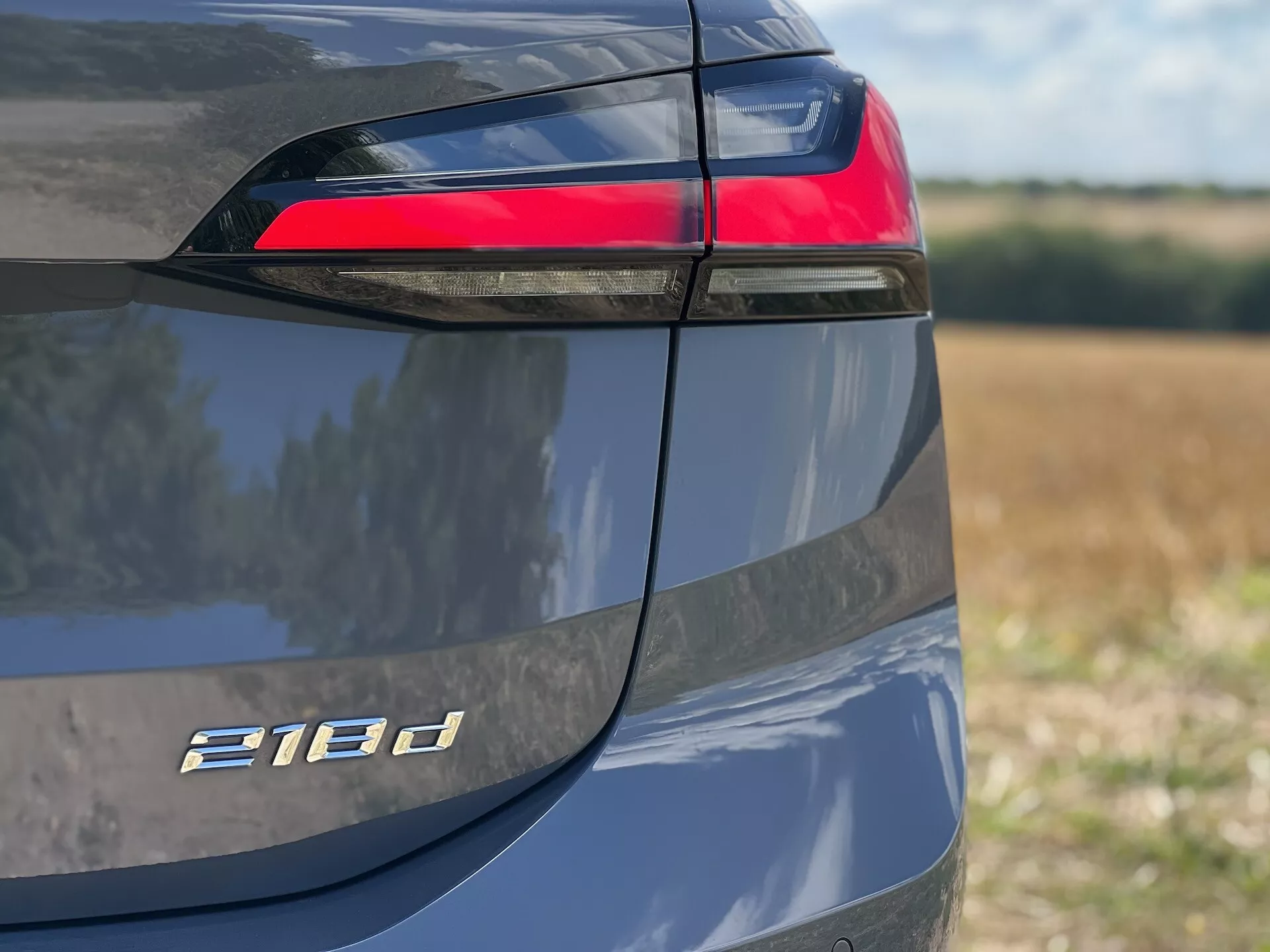 Zbliżone ujęcie lewego tylnego boku BMW Serii 2 Active Tourer 218d z naciskiem na tylny zespół świateł LED, oznaczenie modelu i metaliczne wykończenie lakieru w świetle dziennym