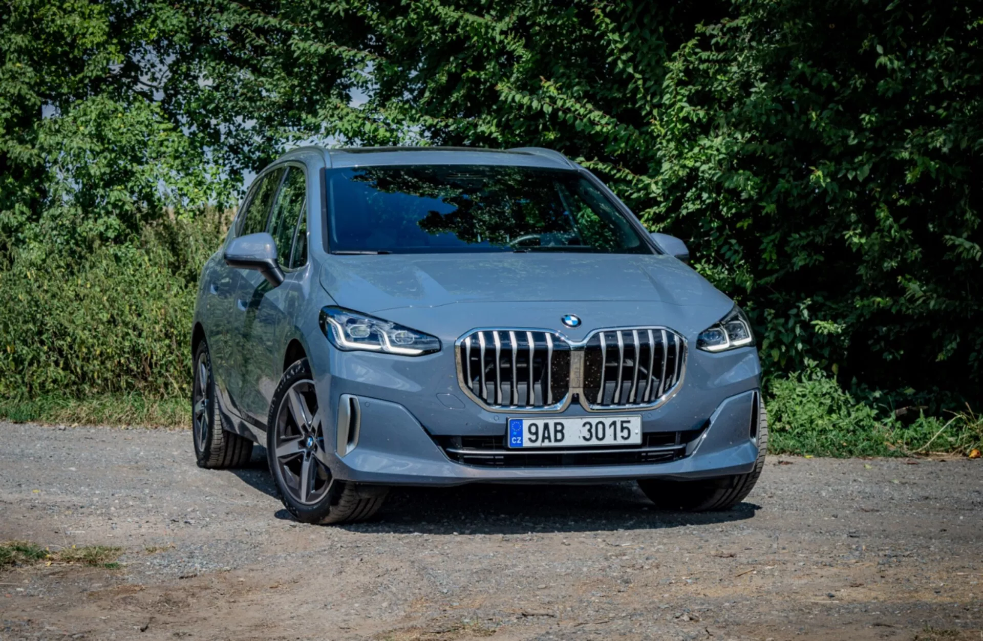 BMW Serii 2 Active Tourer z 2022 roku zaparkowane na żwirze, pokazujące swój sportowy design i nowoczesne funkcje z perspektywy trzech czwartych z przodu na naturalnym tle