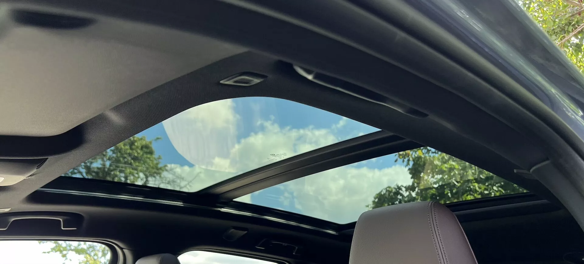Widok wnętrza BMW Serii 2 Active Tourer 2022 z częściowo otwartym dachem panoramicznym i jasnymi elementami wnętrza, podkreślającymi przestronność i luksusowe udogodnienia.