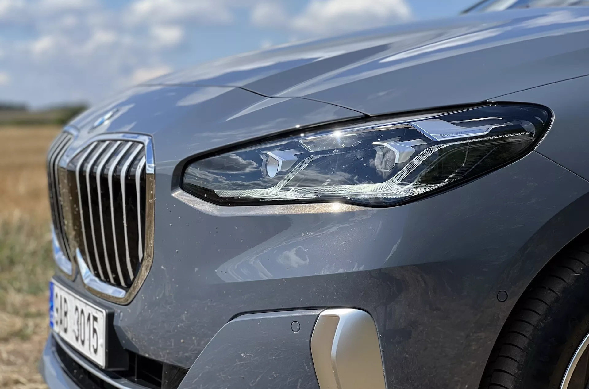 Zbliżenie na przedni lewy kwartał BMW Serii 2 Active Tourer 2022 z akcentem na zestaw reflektorów LED, atrapę z pionowymi prętami i cechy aerodynamiczne