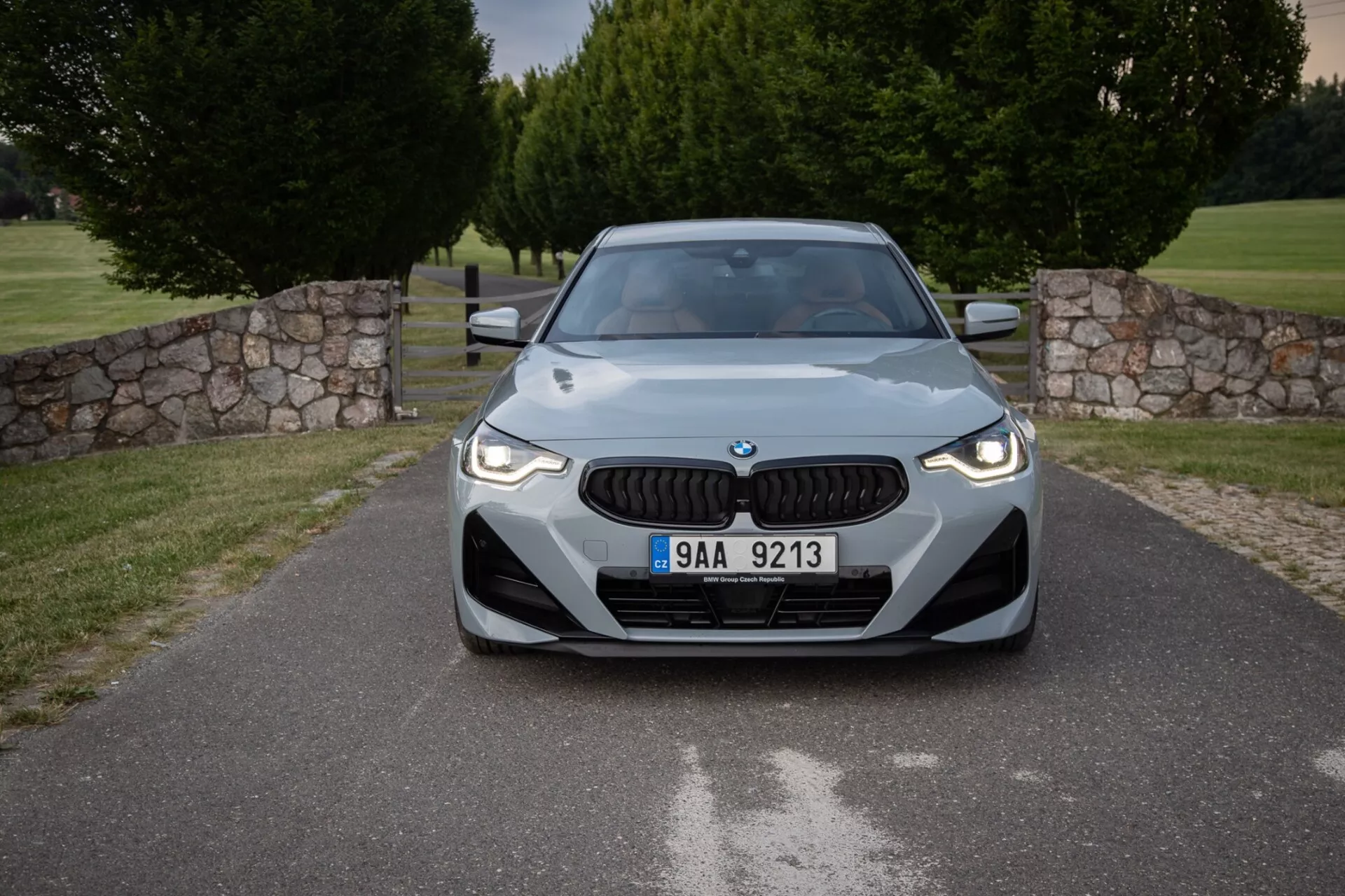Widok z przodu BMW 2er-reihe 2022 (2-series-coupe) w zaaranżowanej przestrzeni zewnętrznej, z charakterystycznym grillem marki, eleganckimi reflektorami LED i aerodynamicznie ukształtowaną maską, podkreślającymi nowoczesny design i technologiczne cechy, w tym potencjalne czujniki do zaawansowanych systemów wspomagania kierowcy.