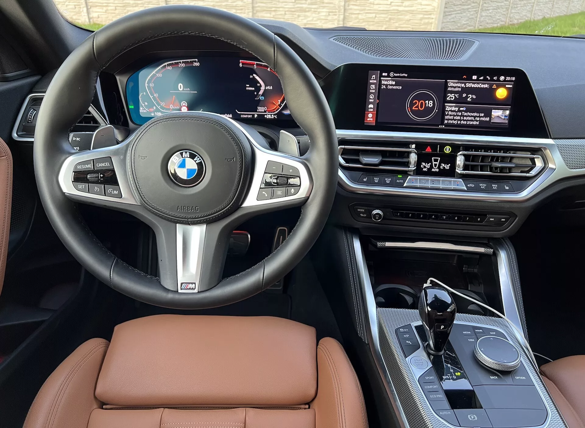 Zdjęcie wnętrza BMW 2er-serii 2022 ukazujące deskę rozdzielczą, kierownicę i konsolę środkową. Cechy obejmują cyfrowy panel instrumentów, wielofunkcyjną kierownicę, duży system infotainment z ekranem dotykowym, obrotowy pokrętło sterowania na konsoli środkowej, dźwignię zmiany biegów o automatycznej skrzyni biegów z sportowym designem i wysokiej jakości skórzane fotele, cały obrazek widziany z perspektywy siedzenia kierowcy w naturalnym świetle dziennym.
