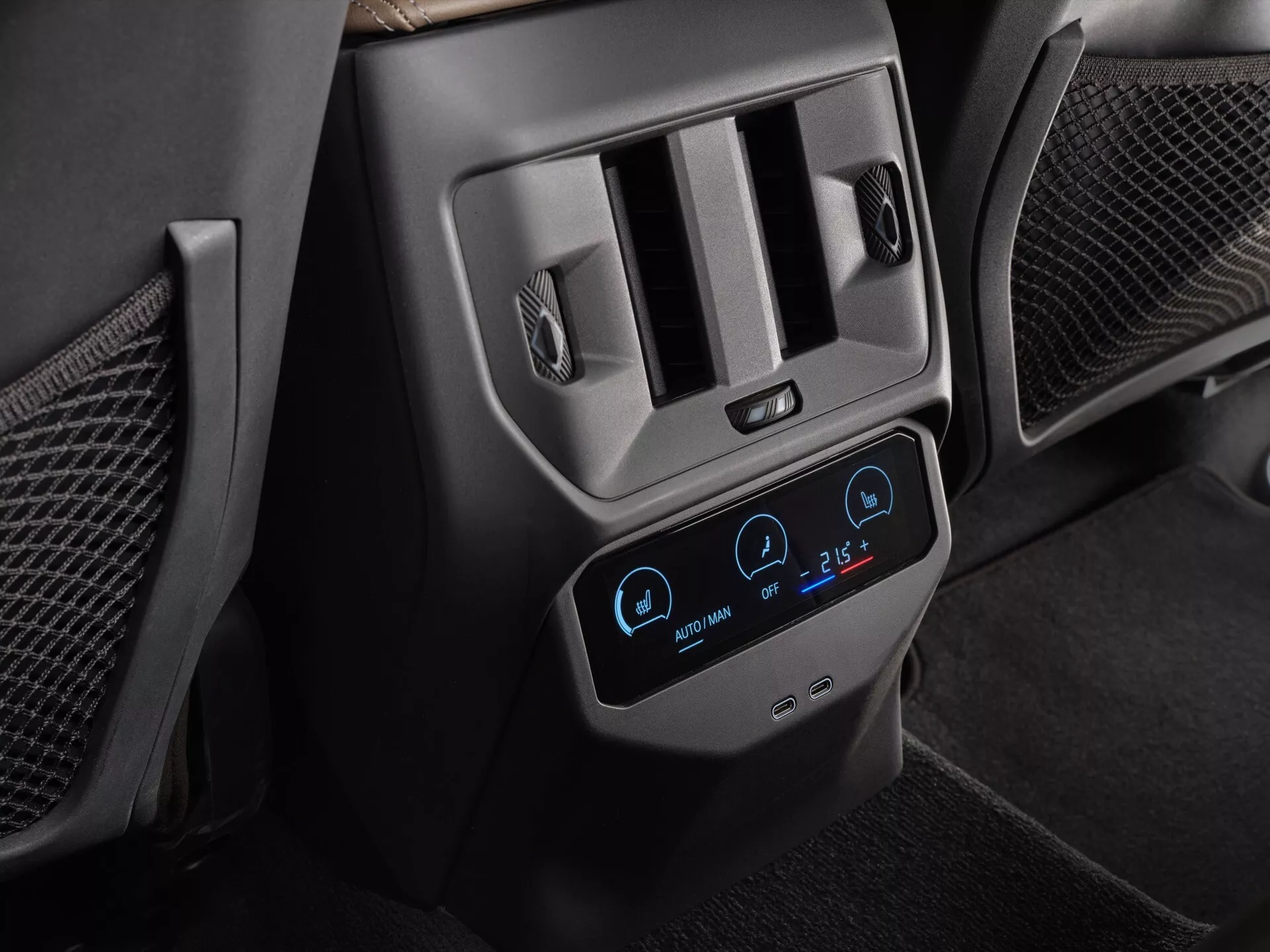 Zbliżenie na tylny system klimatyzacji BMW X3 2024 (G45), skupiający się na nowoczesnym panelu dotykowym z niebieskim podświetleniem, pokazującym ustawienia dwustrefowe na 22°C i 26°C, otoczonym metalicznymi wylotami powietrza oraz ikonami podgrzewania siedzeń, w ciemnym wnętrzu z czarnej skóry i plastiku, podkreślającym zaawansowane funkcje komfortu i wygody pasażerów.