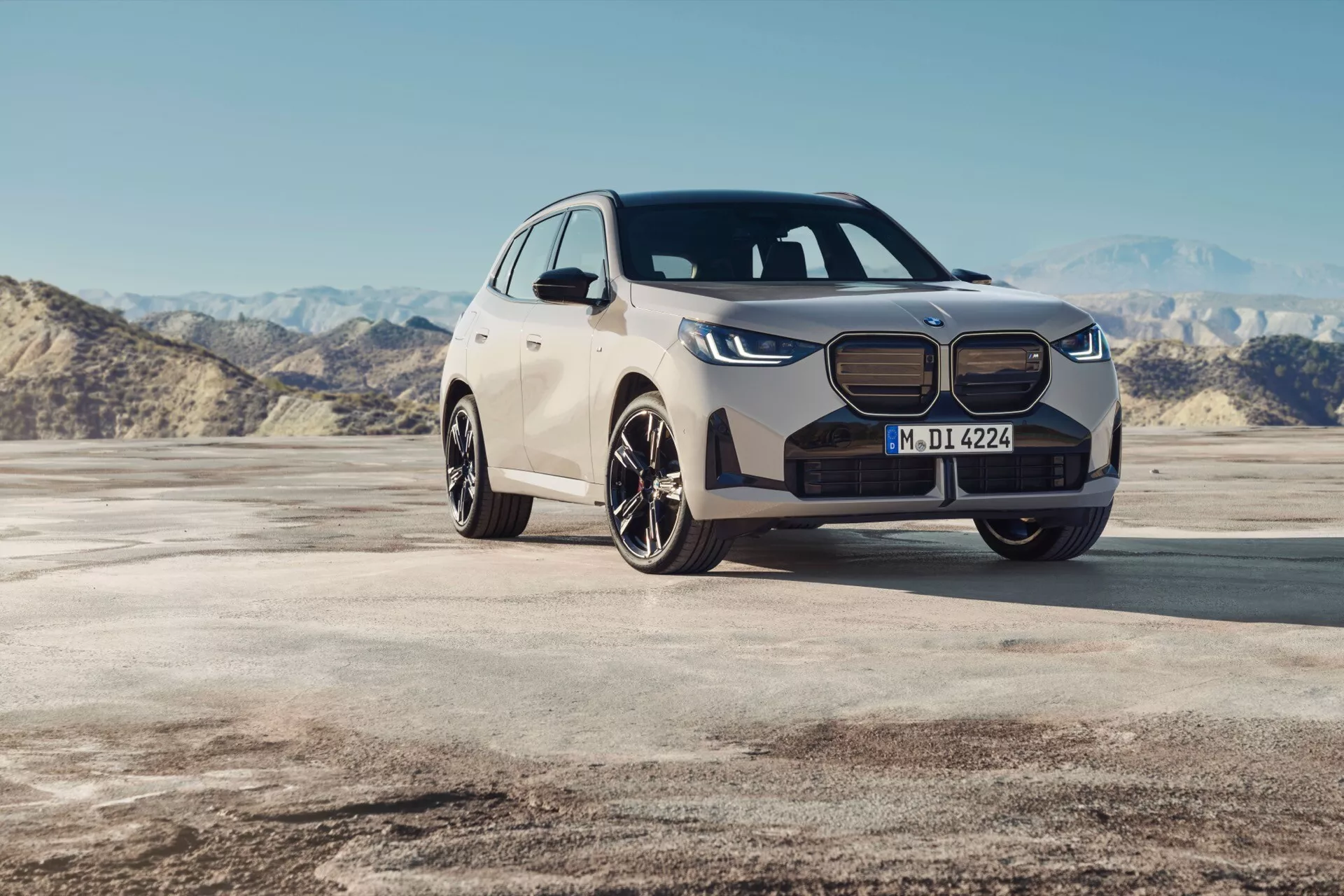 Widok z przodu z trzech czwartych BMW X3 2024 (G45) w naturalnym świetle dziennym, prezentujący nowoczesny design, ikoniczne podwójne reflektory, wyeksponowaną przednią kratkę i wieloszprychowe felgi aluminiowe w otwartym środowisku.