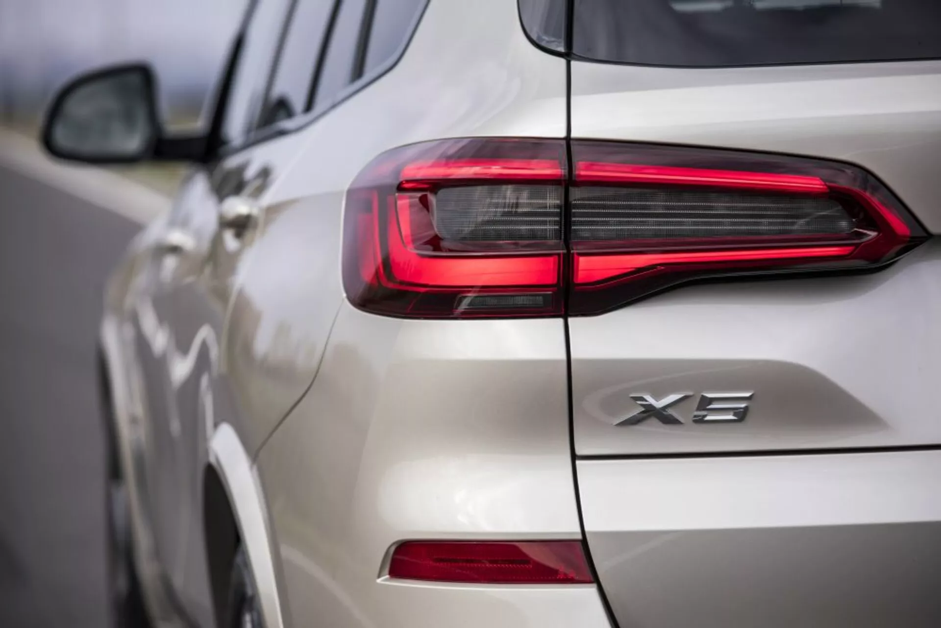 Zbliżony widok tylnej części białego BMW X3 2018, prezentujący projekt tylnego światła LED i oznaczenie X3, skupiający się na nowoczesnym, poziomym podpisie świetlnym i szczegółach na klapie bagażnika i boku.