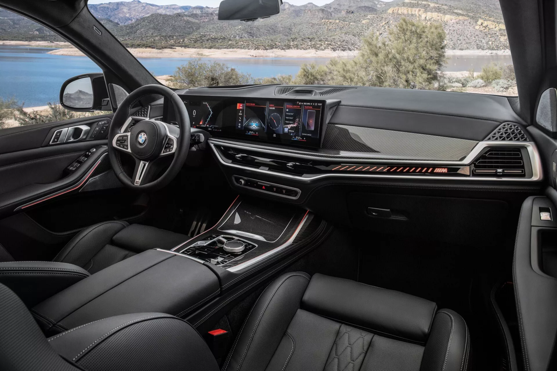 Wnętrze BMW X7 (G07-facelift) z 2022 roku przedstawiające wielofunkcyjną kierownicę obszytą skórą z logo producenta, cyfrowy panel przyrządów, centralny system infotainment z dotykowym ekranem oraz materiały premium, w tym skórzane siedzenia z zaawansowanymi funkcjami klimatyzacji z perspektywy przedniego pasażera
